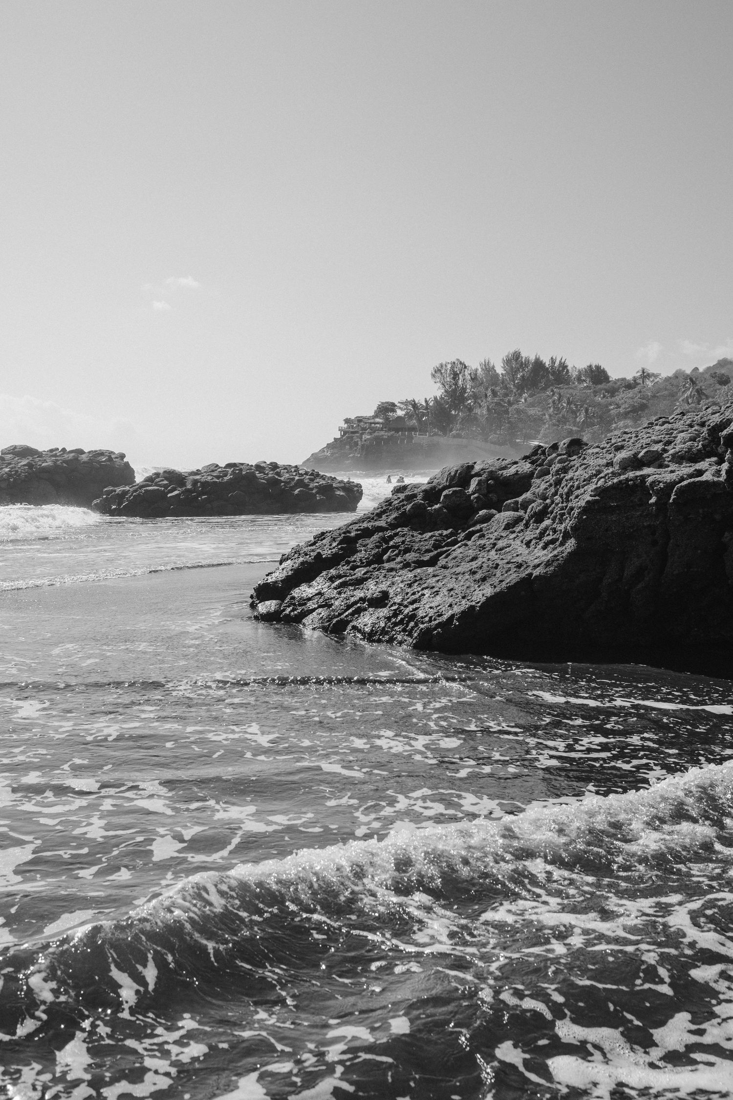 Dramatic black and white seascape with waves crashing against rocky cliffs.
