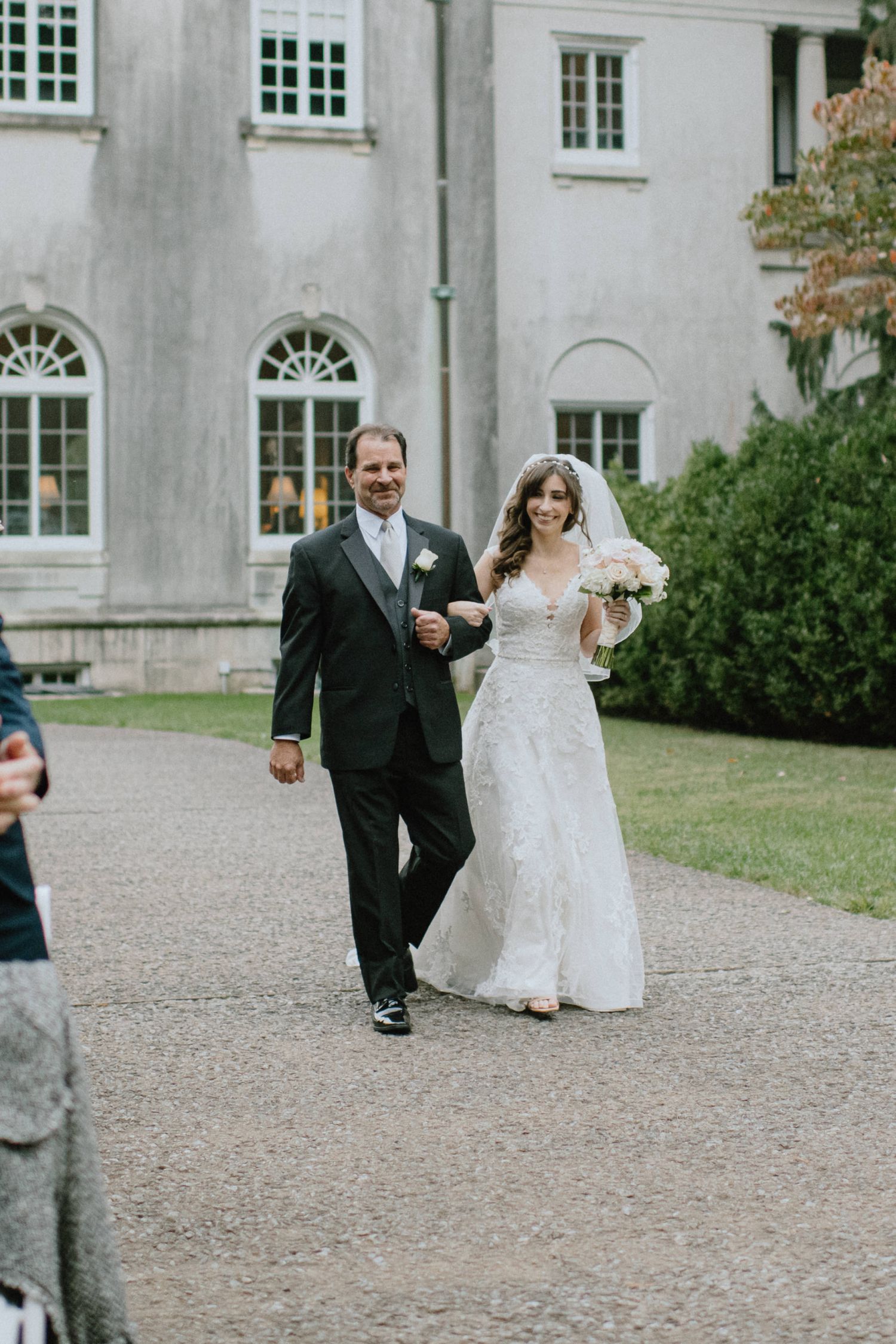 bride enters ceremony with father strong mansion in the background