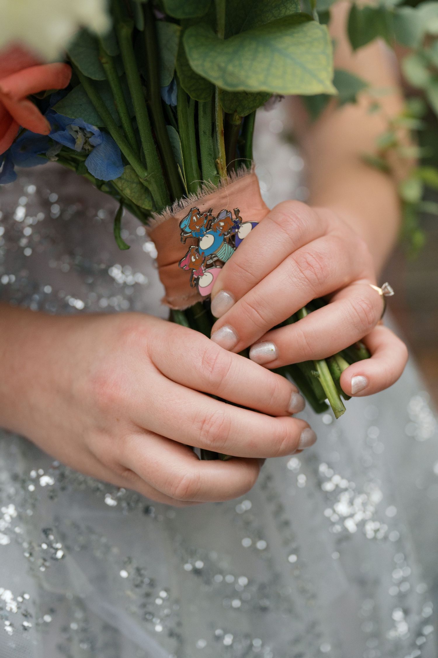 Close-up of hands holding a bouquet with a delicate turquoise ring detail.