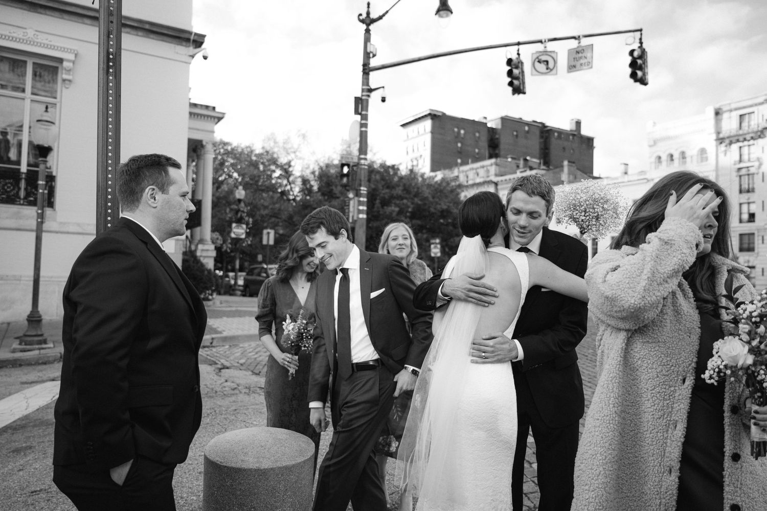 Black and white photo of wedding guests gathered on a city street corner.