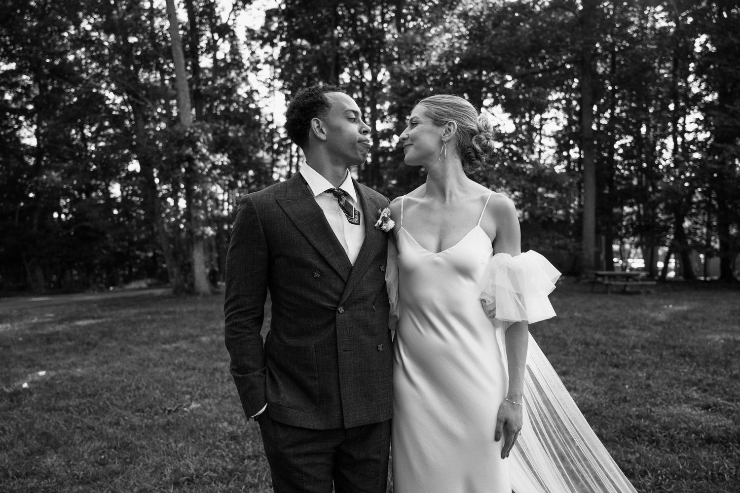 A romantic black and white portrait of newlyweds sharing an intimate moment in a garden setting.