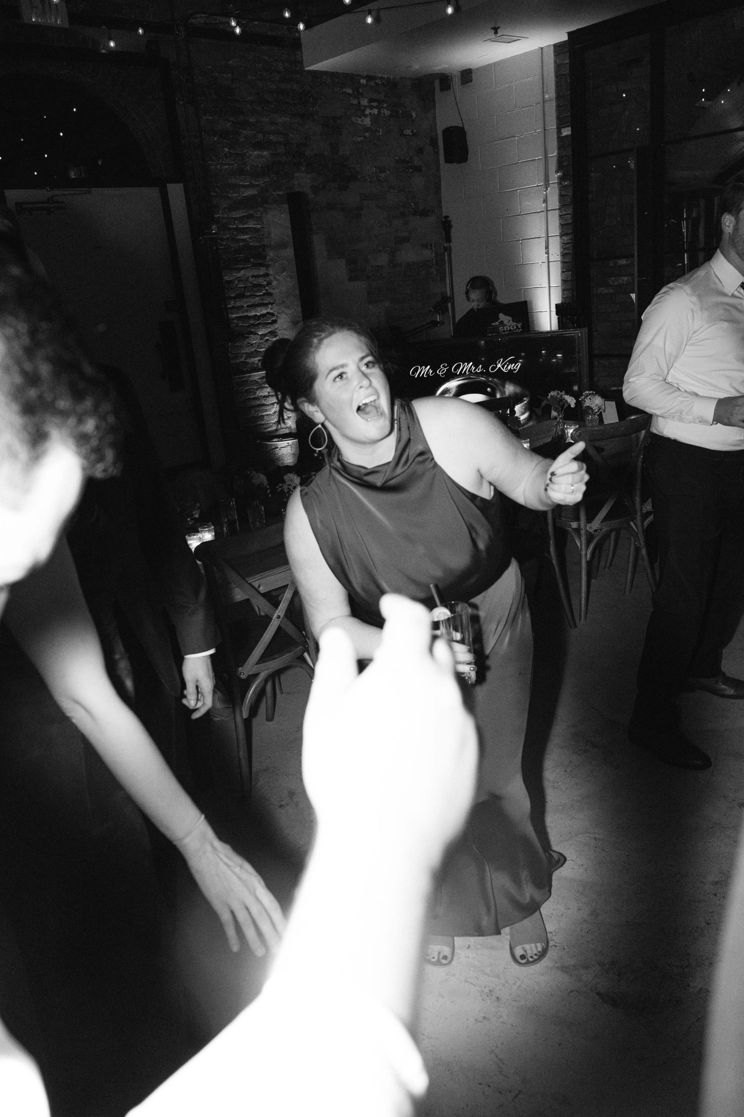 Black and white photo of people dancing energetically at a dimly lit party or nightclub event.