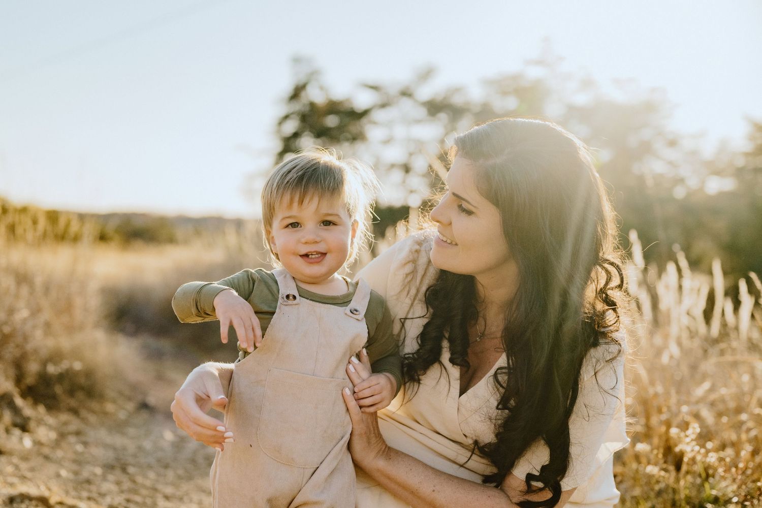A candid moment captured in golden sunlight with tall grass in the background.