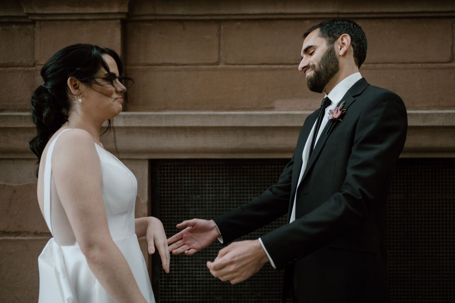 Intimate moment between wedding couple against classic stone architecture.