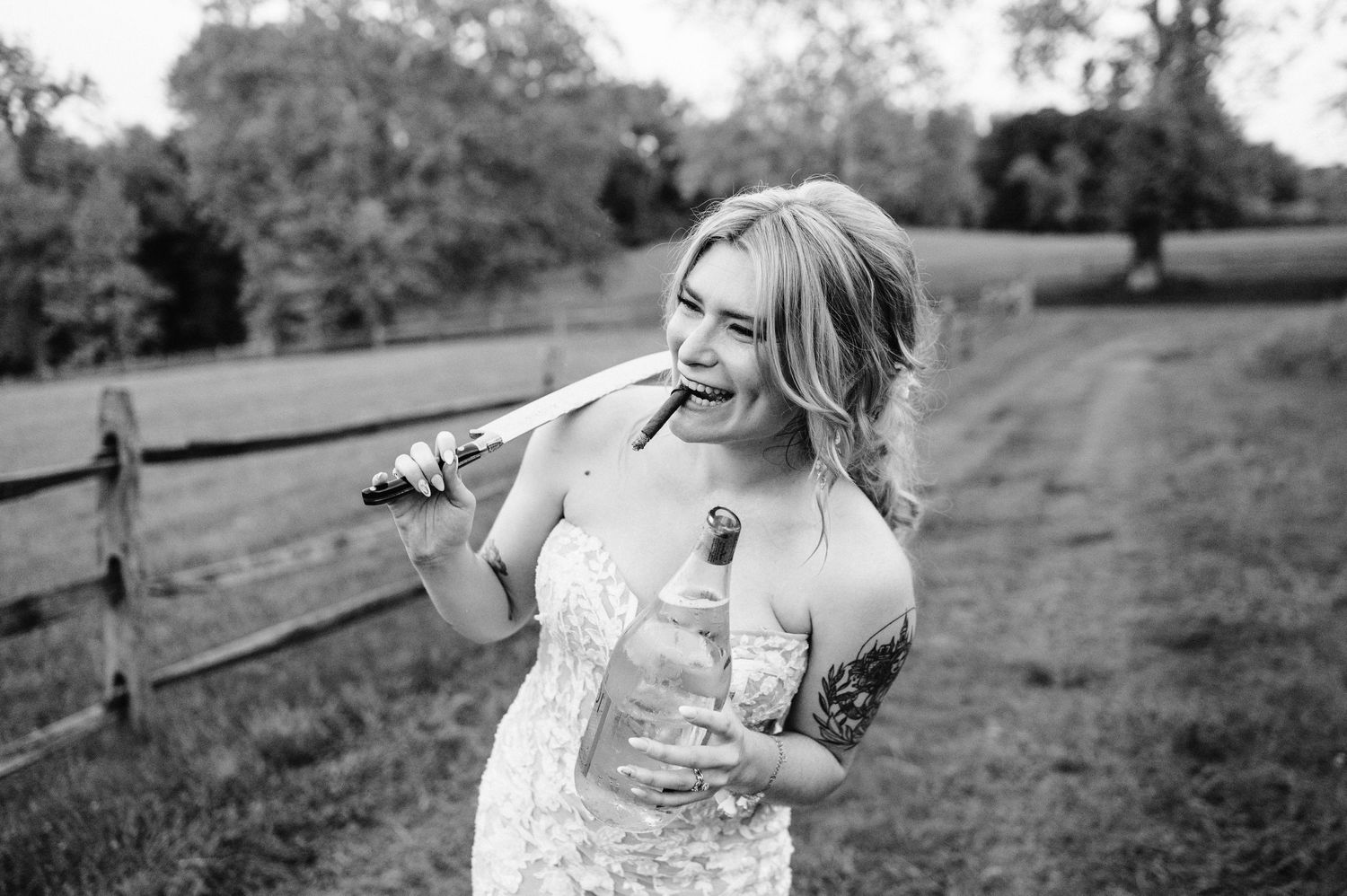 A candid black and white portrait of someone laughing in a wedding dress outdoors.