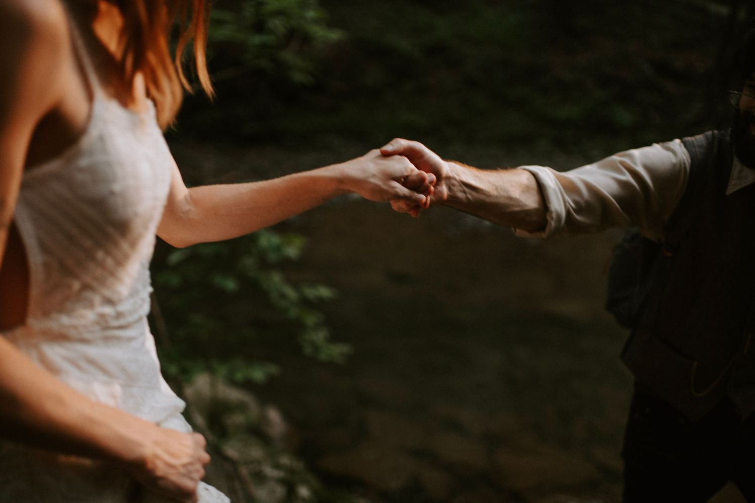 Close-up of joined hands against a forest backdrop.