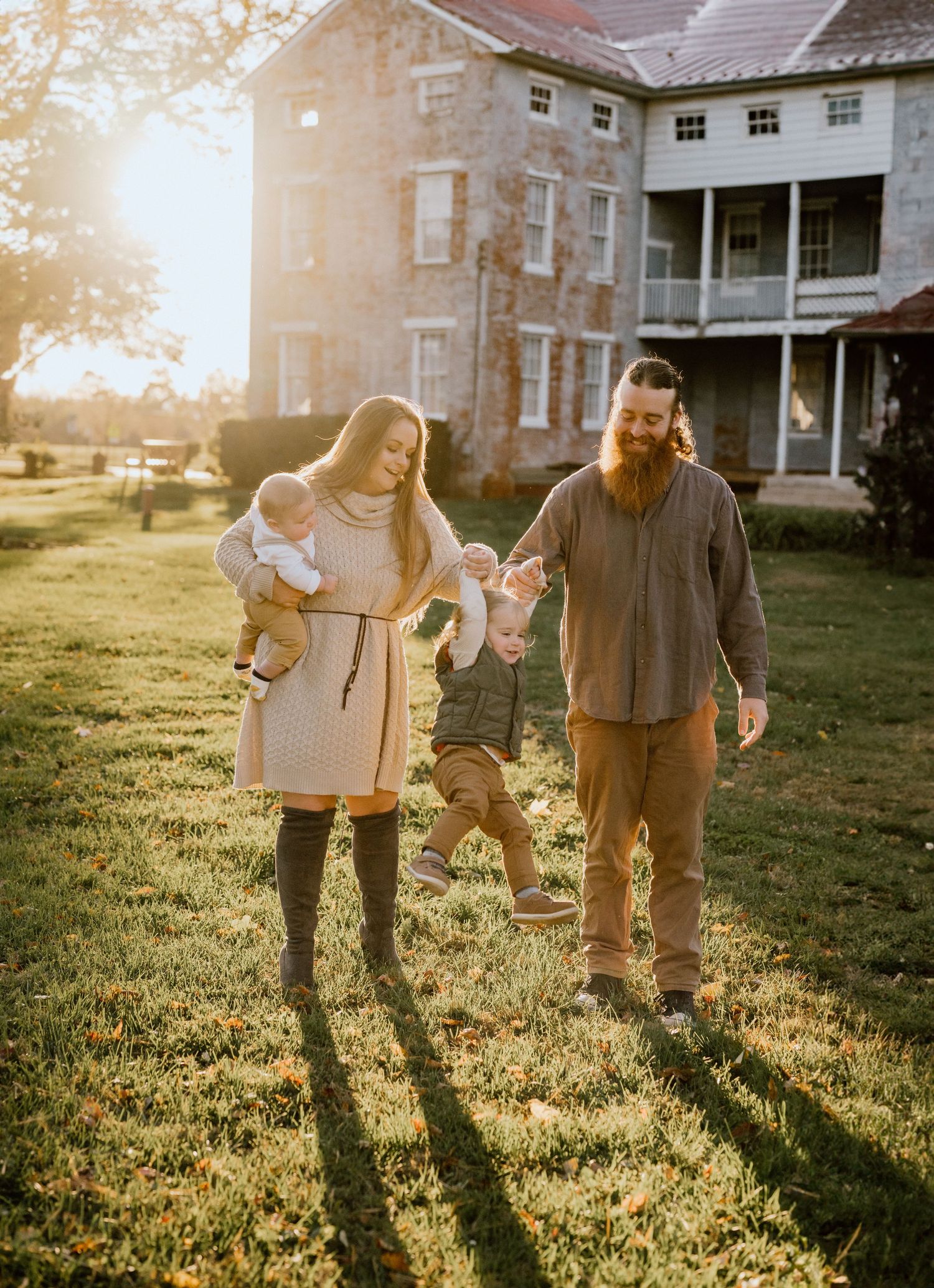A family enjoys playtime together during golden hour outside a historic building.
