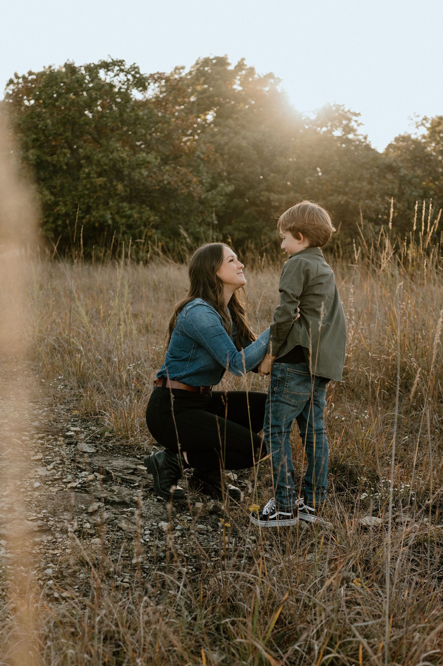 Parent and child sharing tender moment in autumn field at sunset.