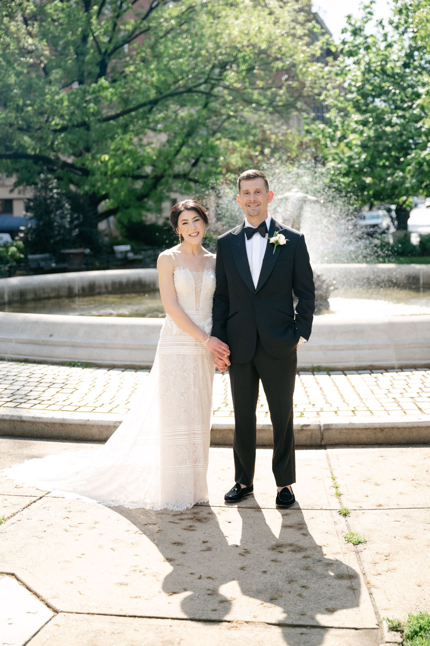 A newlywed couple stands in front of a garden fountain on their wedding day at the Baltimore engineers club.