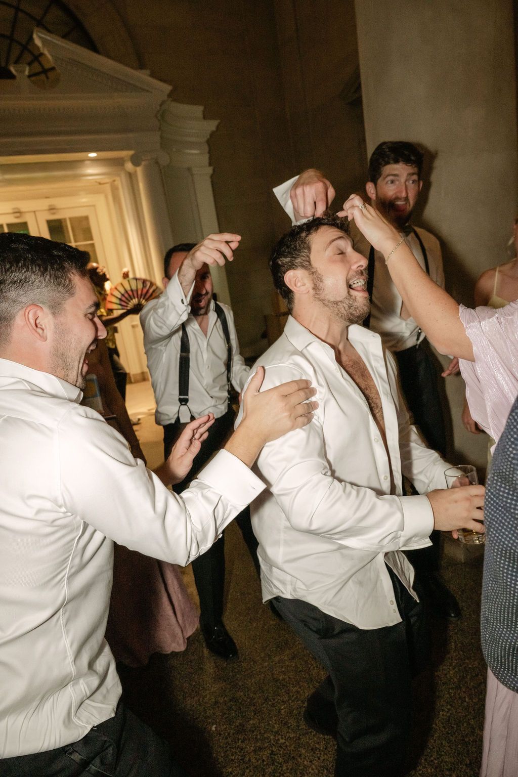 A sequence of party guests dancing and celebrating at a formal event in white dress shirts.