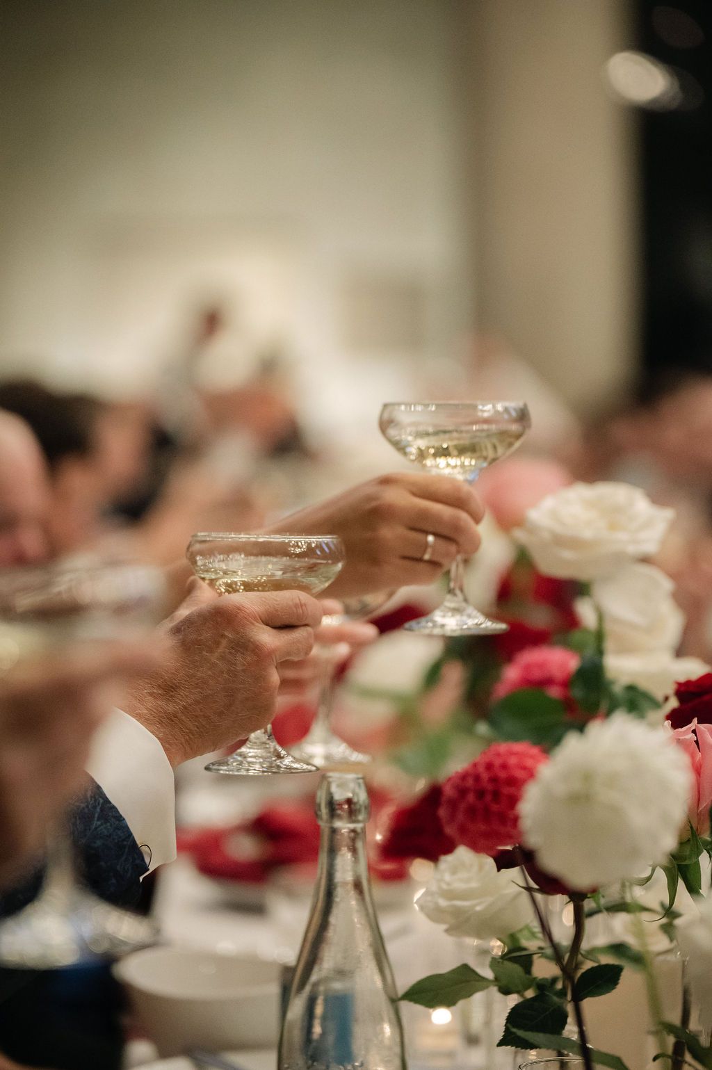 Crystal wine glasses and red roses decorate an elegant table setting at a formal dinner event.