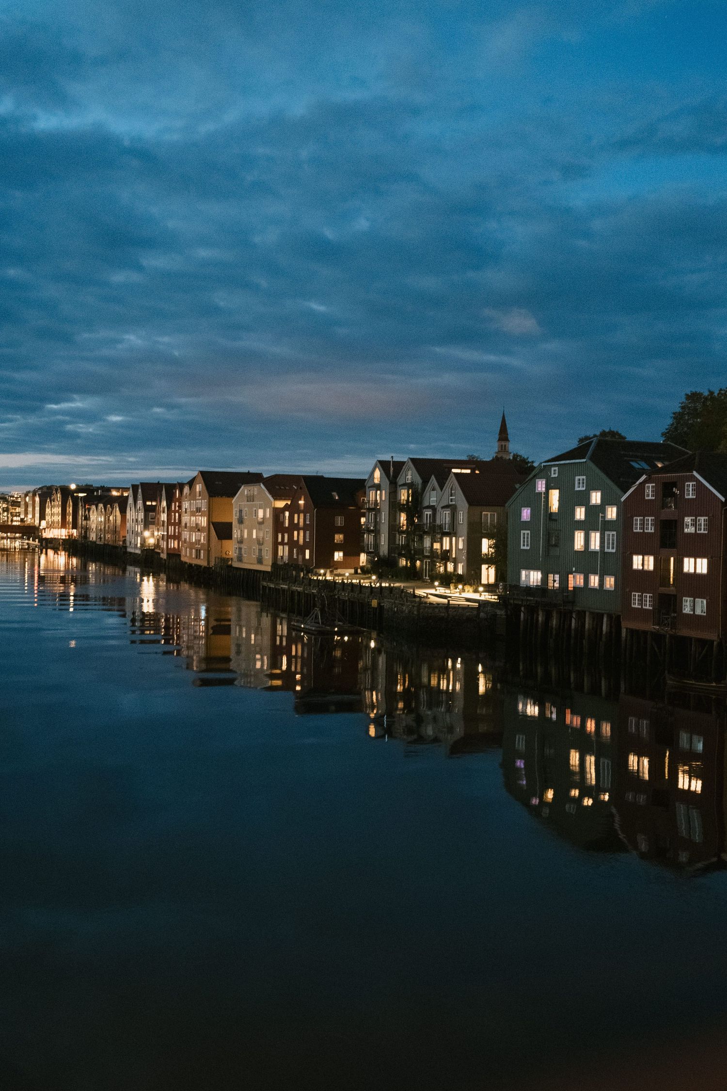 Traditional Norwegian waterfront houses illuminated at dusk with perfect reflections in calm water.