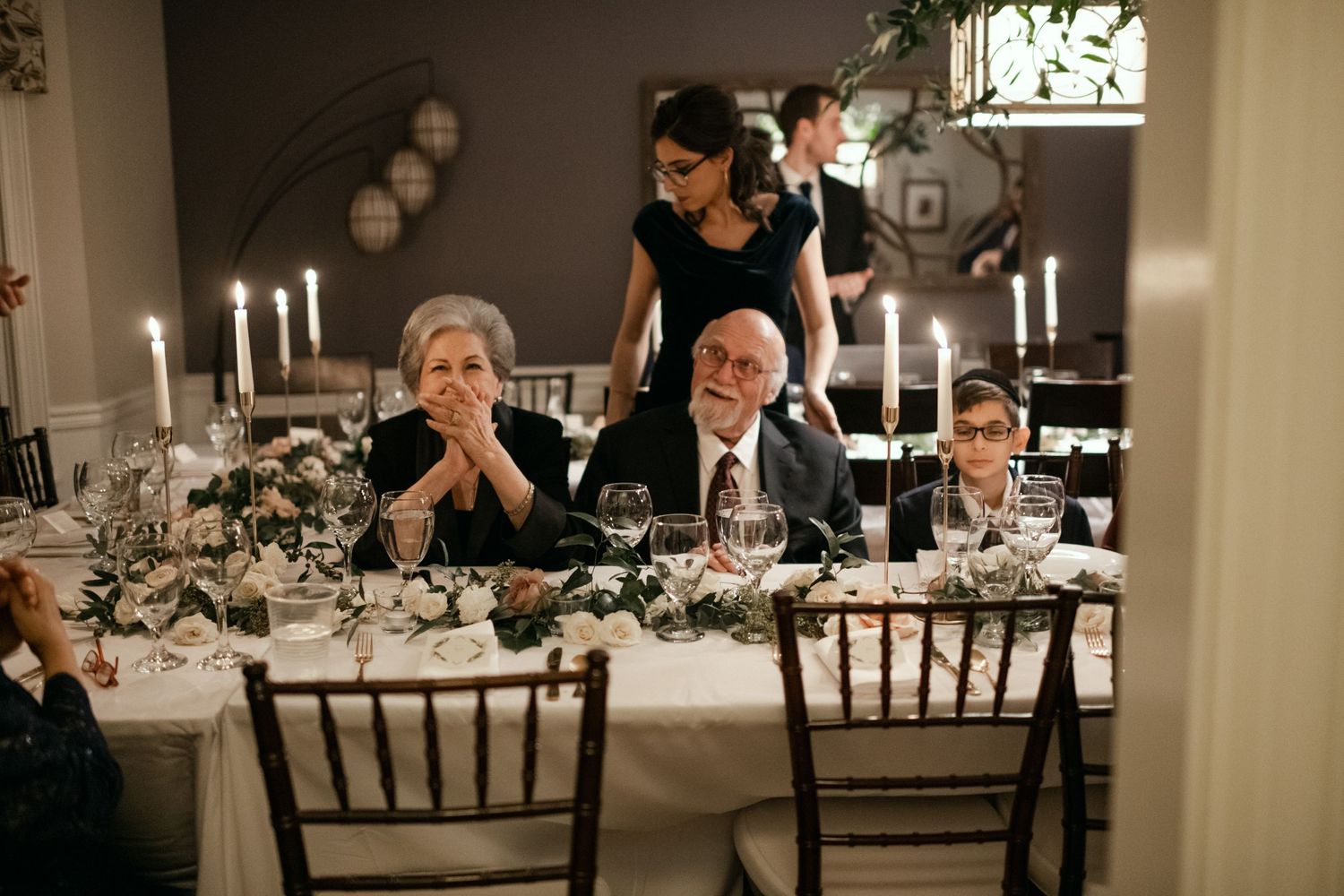Elegant wedding reception table setting with candles and decorative floral arrangements.
