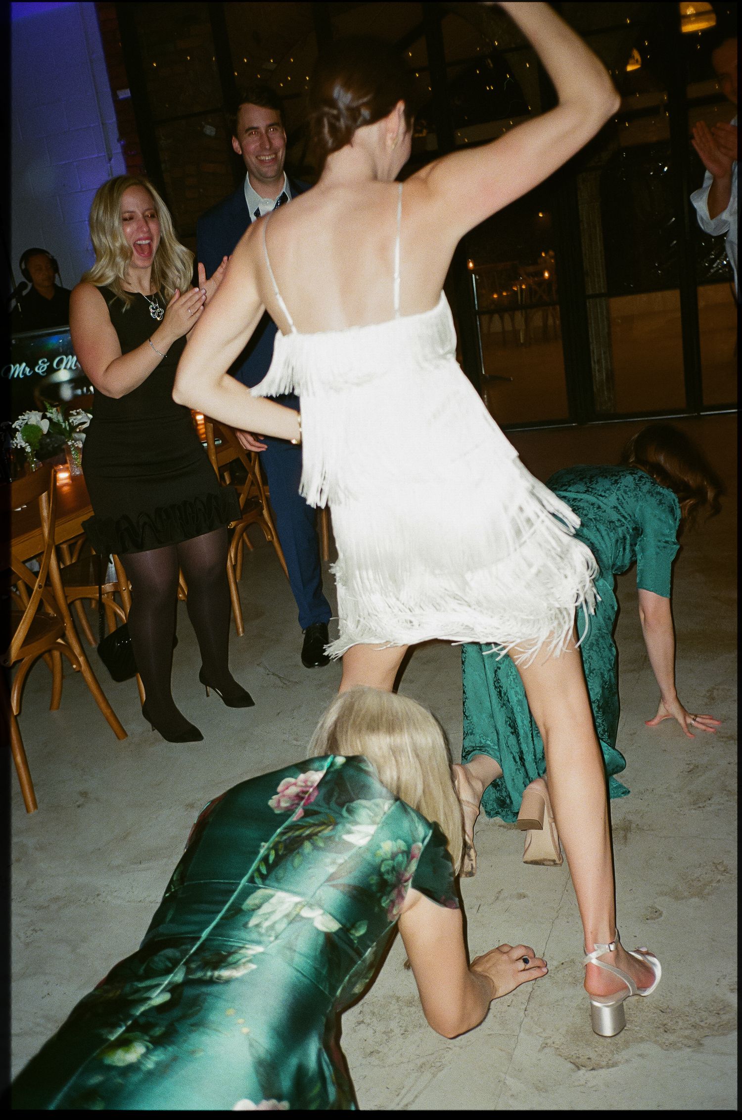 Guests dancing at a party with a woman in a white dress and others in formal attire.