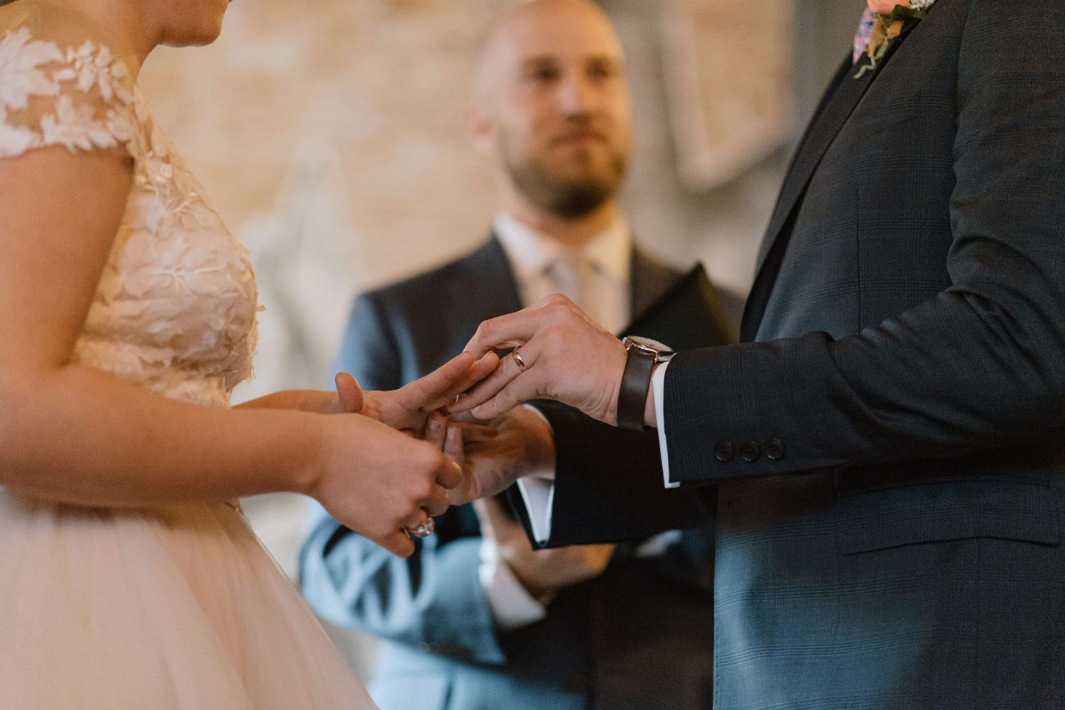 Close-up of hands exchanging rings during an intimate wedding ceremony.