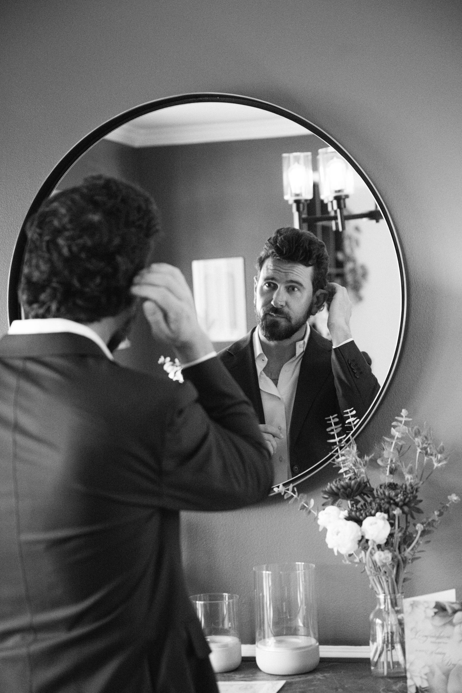 Series of black and white mirror reflections showing someone adjusting their appearance near flower vases.