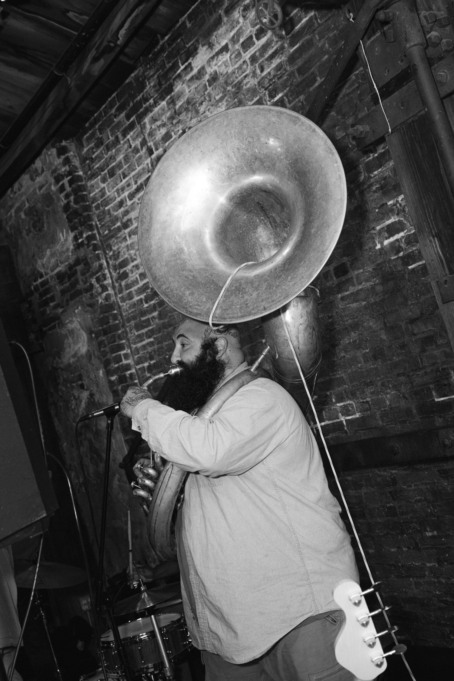 A close-up sequence shows a sousaphone being played in a dark brick-walled venue.