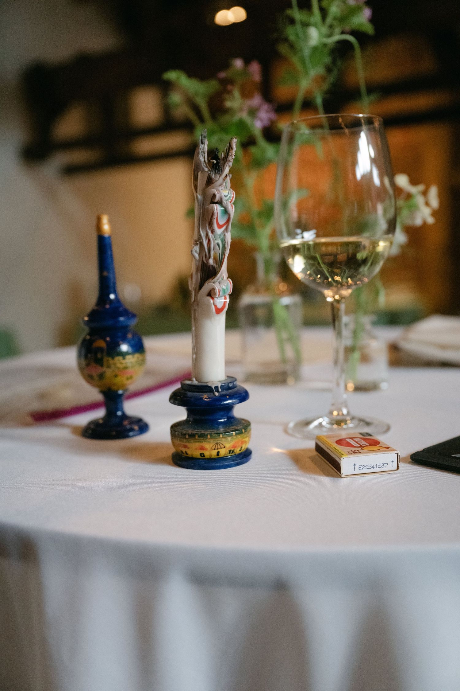 Decorative candles and a wine glass arranged on a white tablecloth.