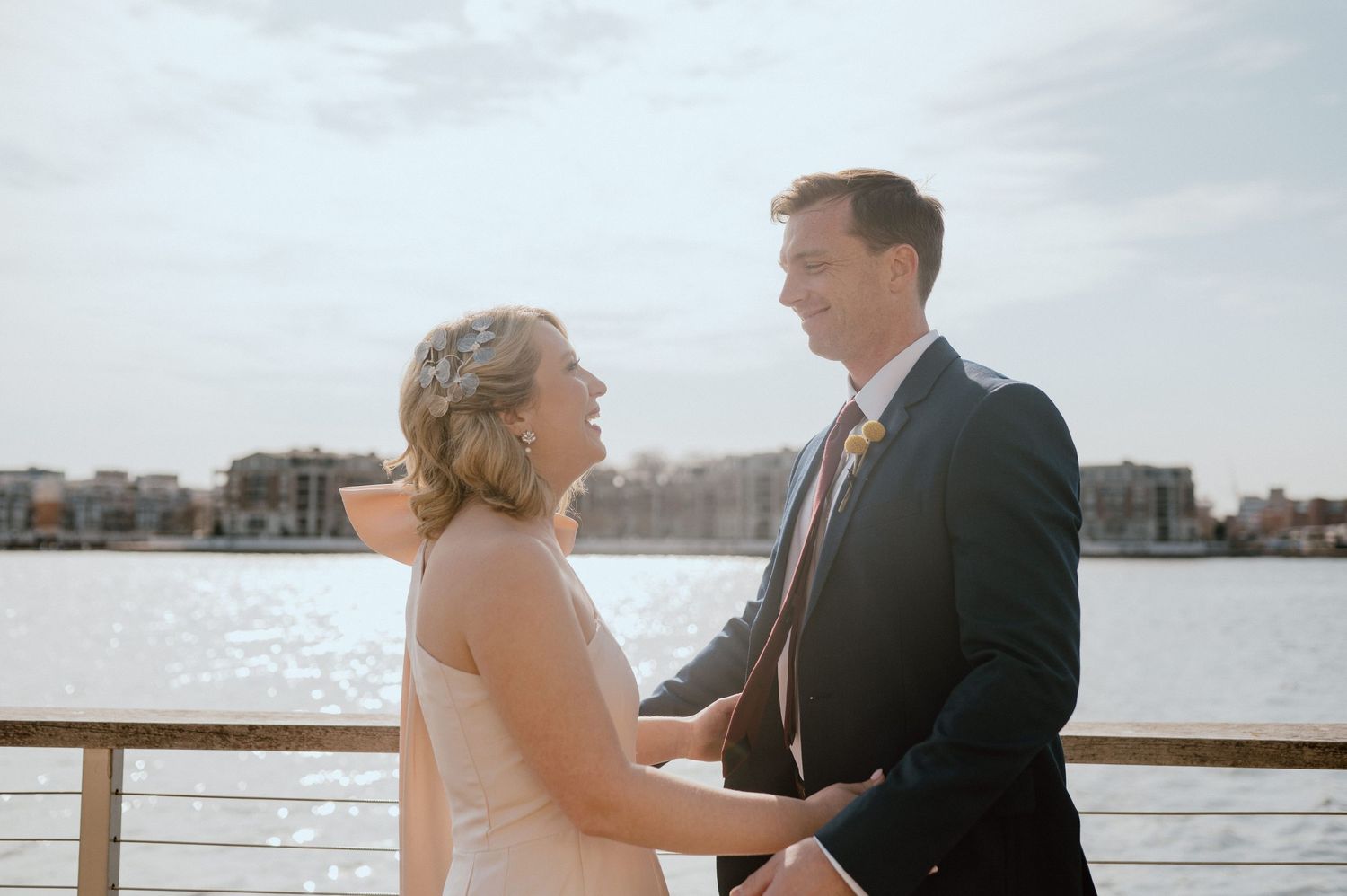 Intimate wedding moment captured on waterfront deck with harbor backdrop.