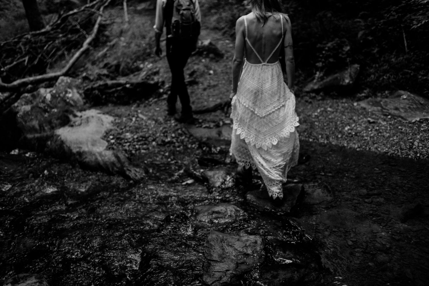 Black and white photo of figures walking along a rocky forest path.