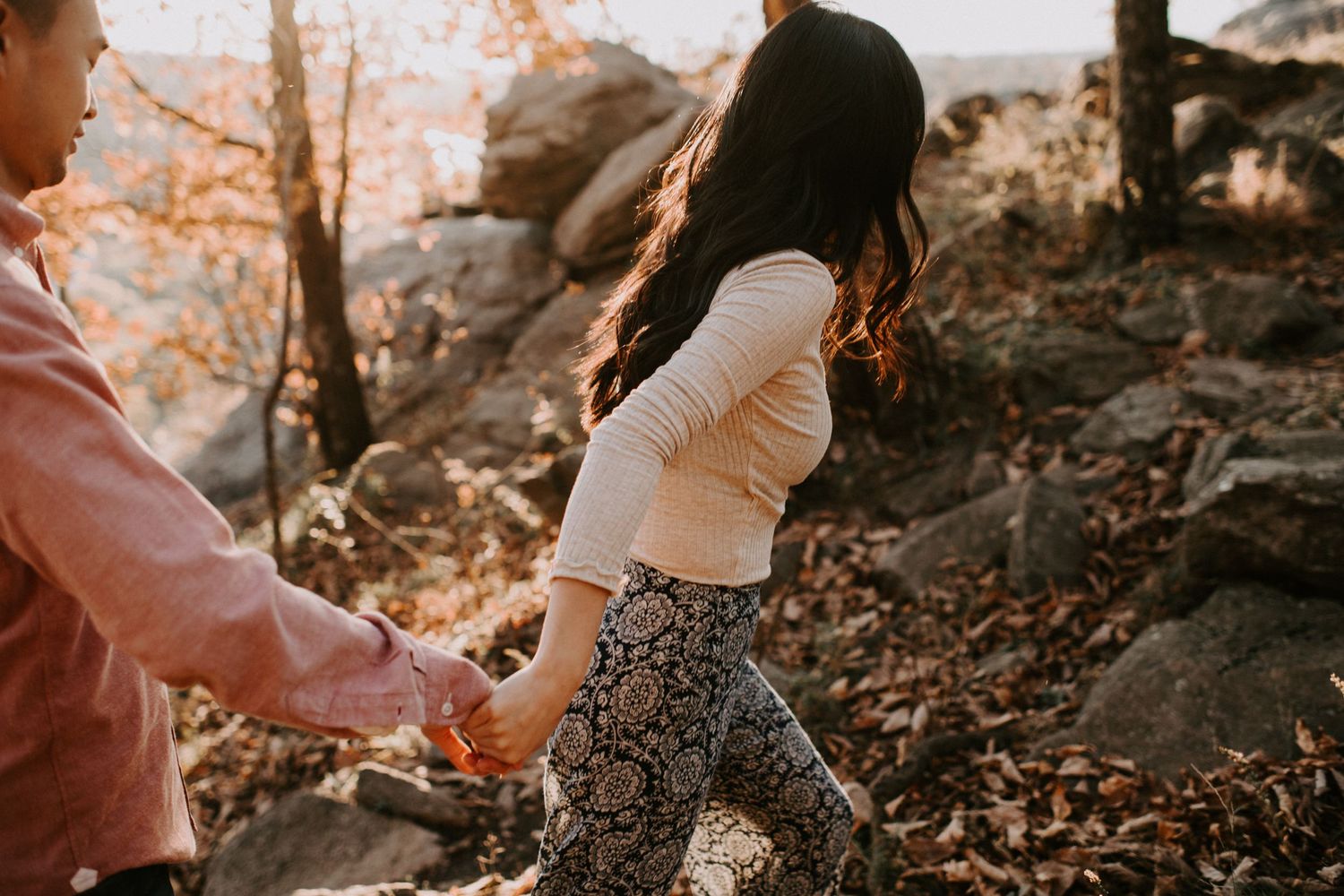 Couple holding hands while exploring rocky terrain during autumn photoshoot.