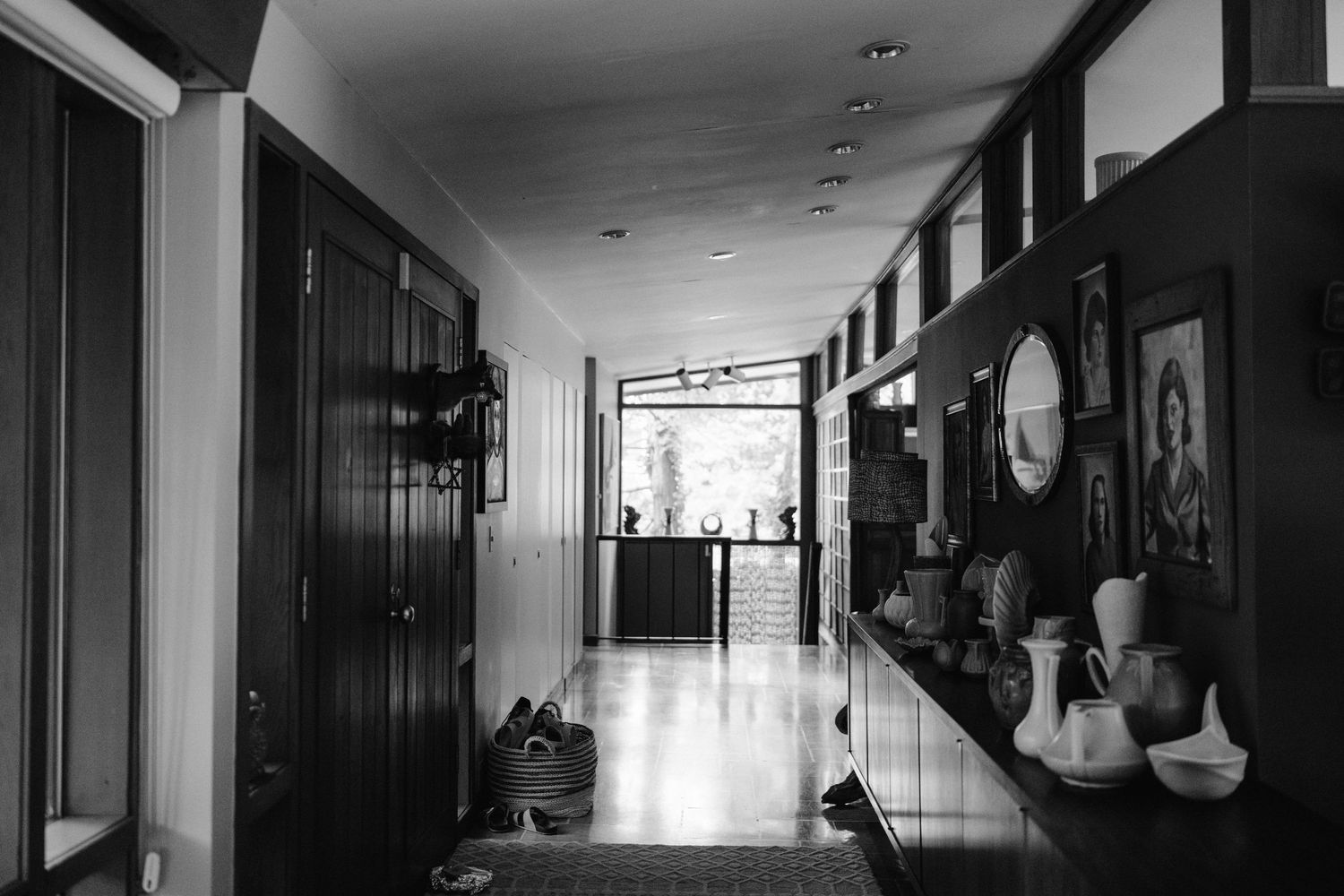 Long hallway with black and white decor featuring vintage artwork and vases.