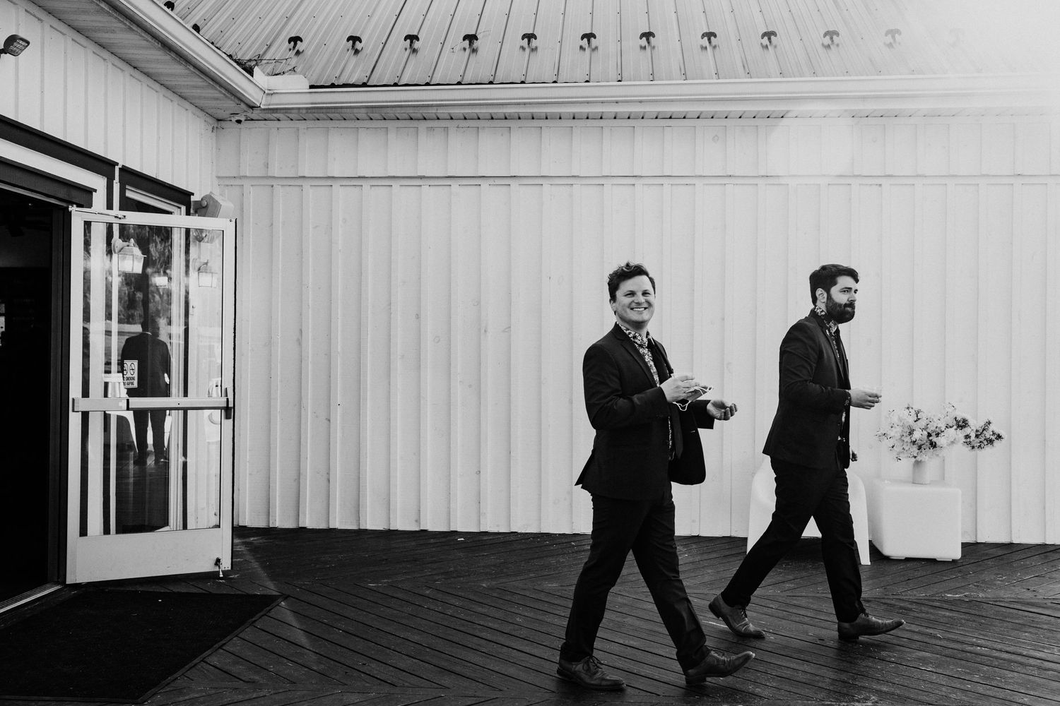 Two people in formal attire walking across a bright indoor venue space.