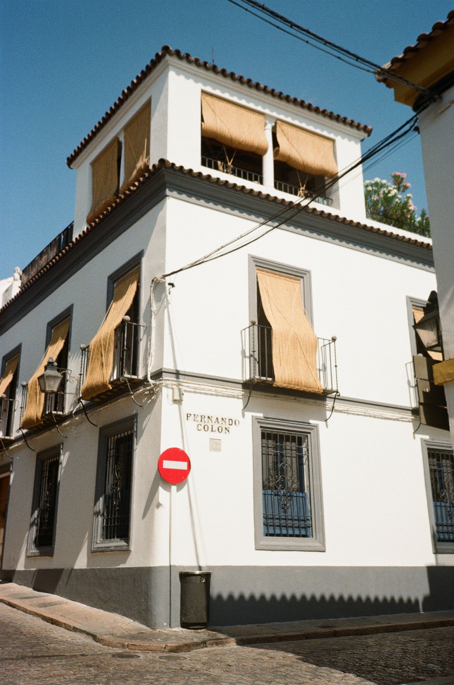 White Spanish-style buildings with awnings on a sloping cobblestone street.