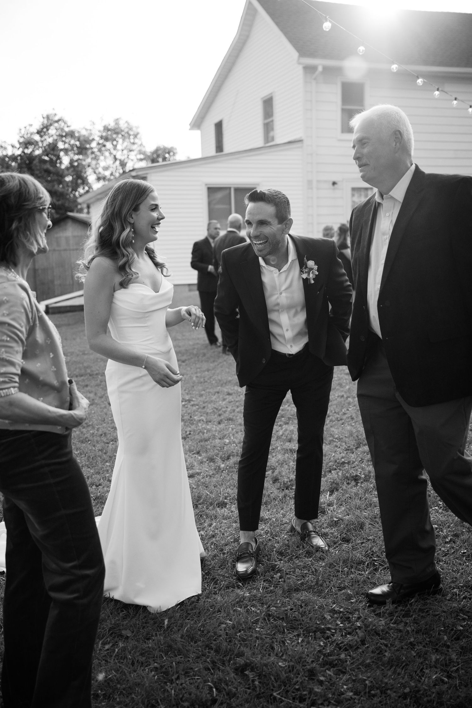 Wedding guests socializing outdoors on grass in formal attire at dusk.