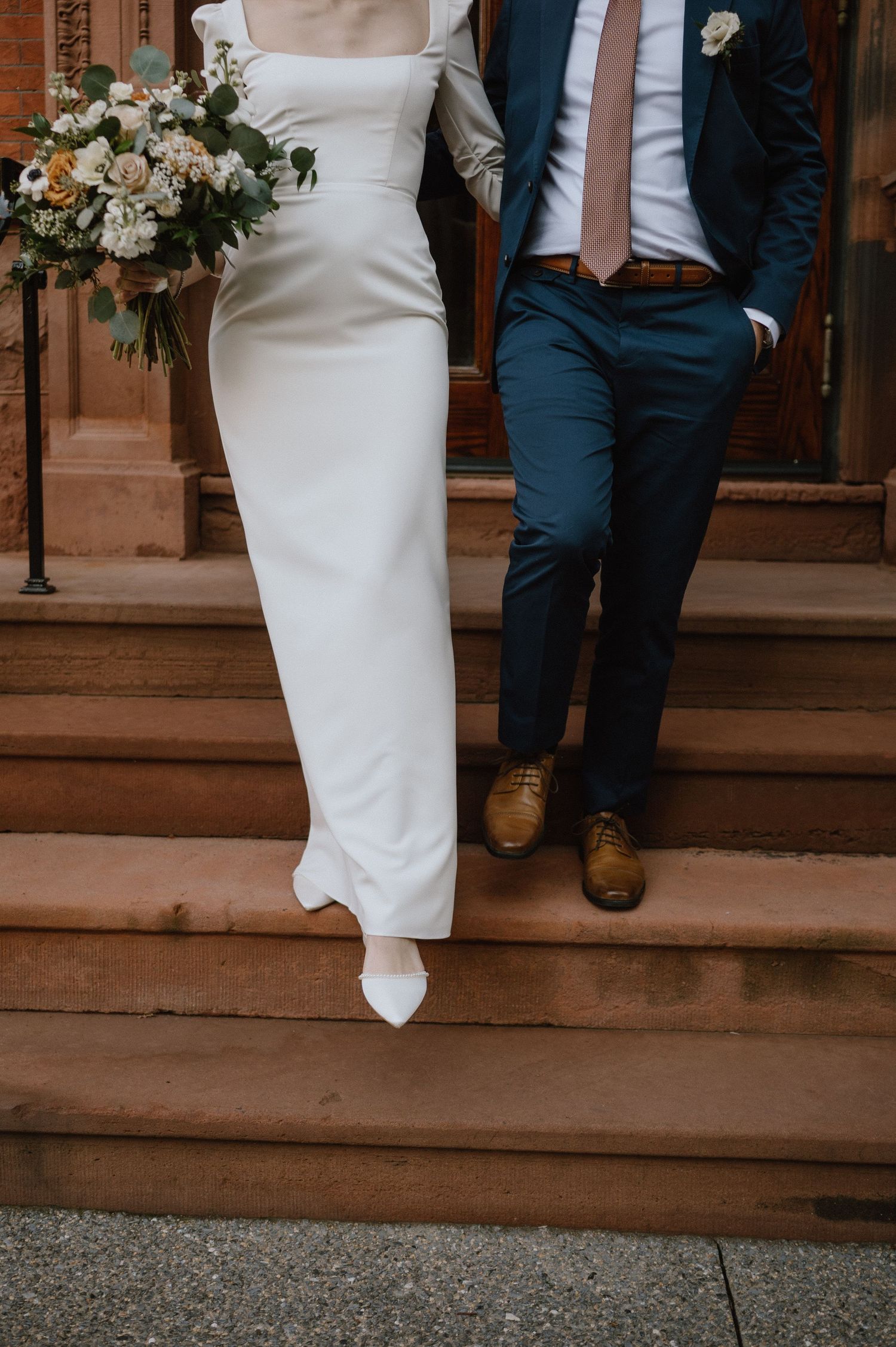 Detail shot of wedding attire and floral bouquet on brick steps.