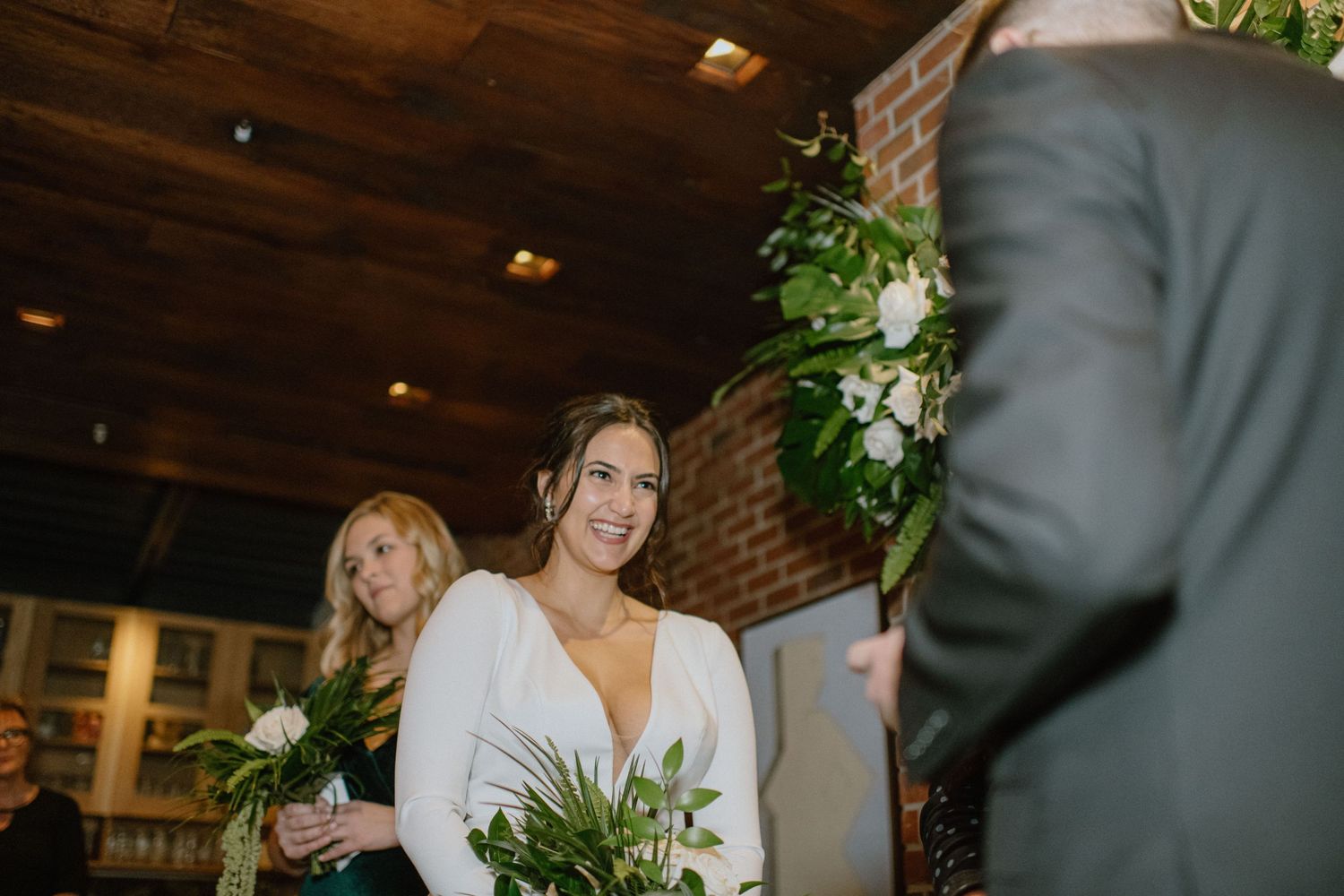 An elegant wedding ceremony in a rustic indoor venue with brick walls and floral decor.