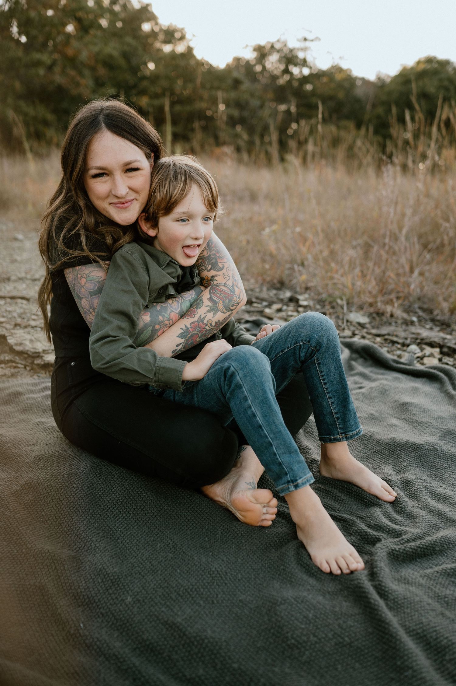 A tender moment between parent and child sitting on a blanket outdoors during sunset.