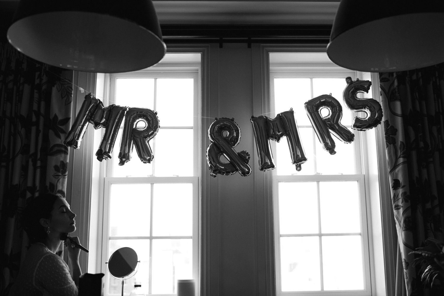 Black and white photo of Mr & Mrs balloon decorations hanging between windows.