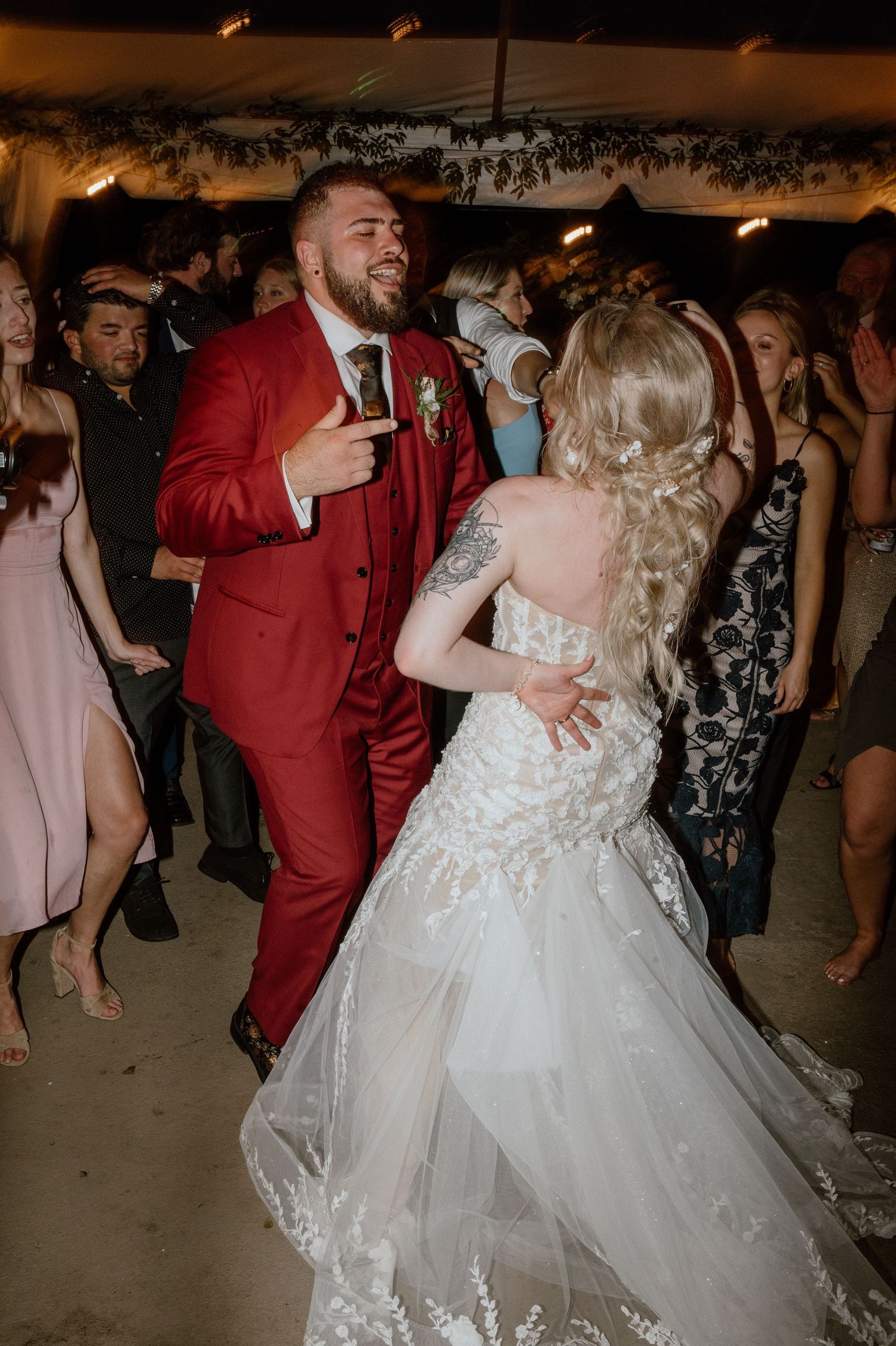 A couple in formal attire dancing at their wedding reception with guests in the background.
