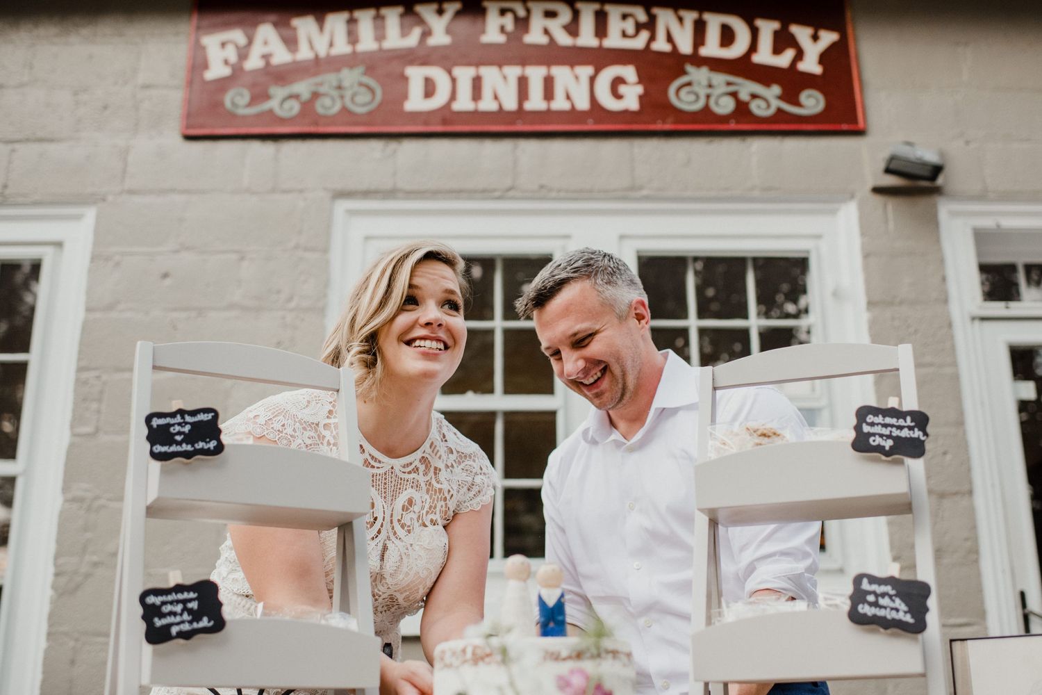 A couple stands outside a family-friendly dining establishment with desserts on display.