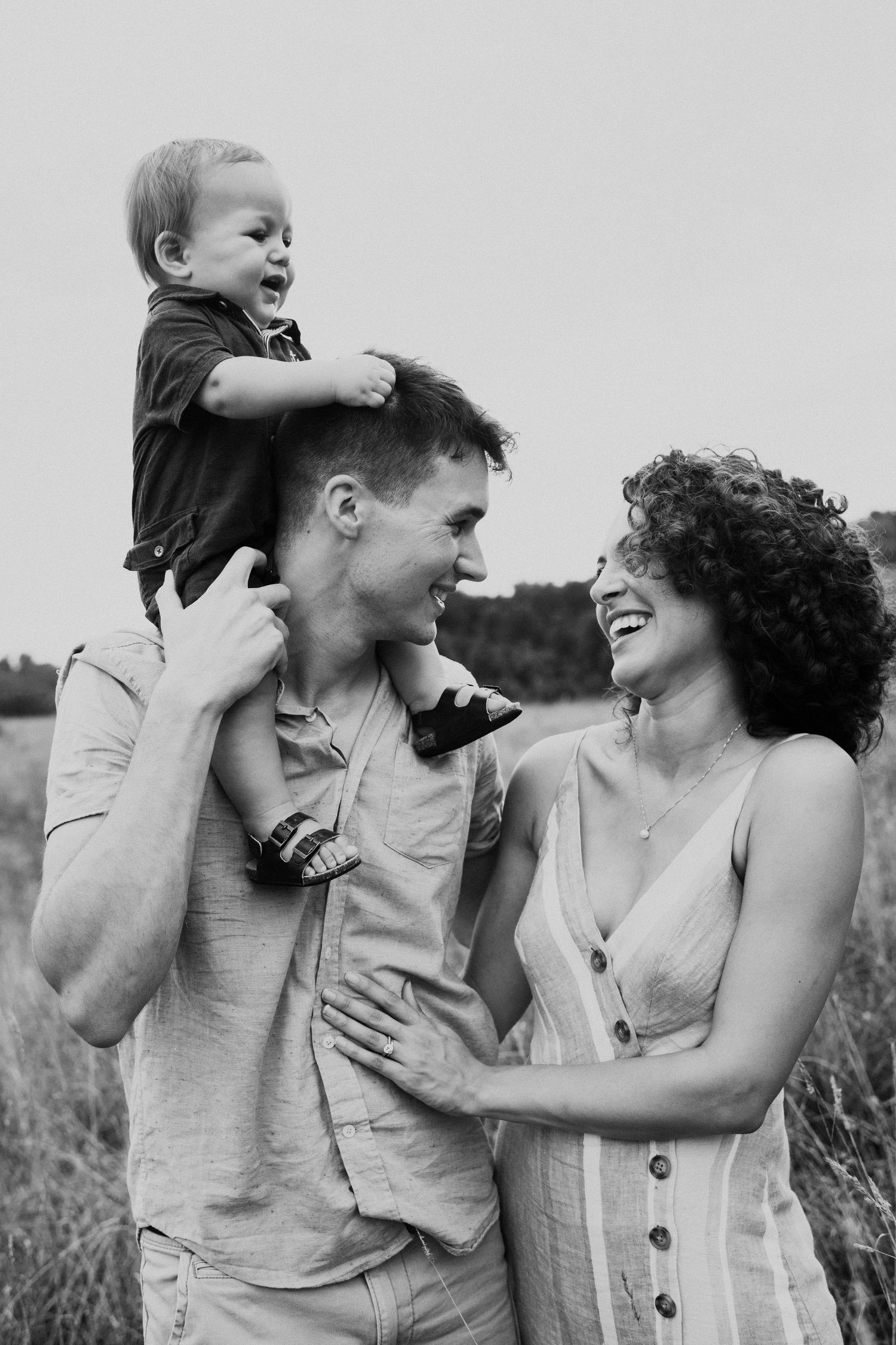 Candid black and white portrait of family sharing laughter during outdoor photoshoot.