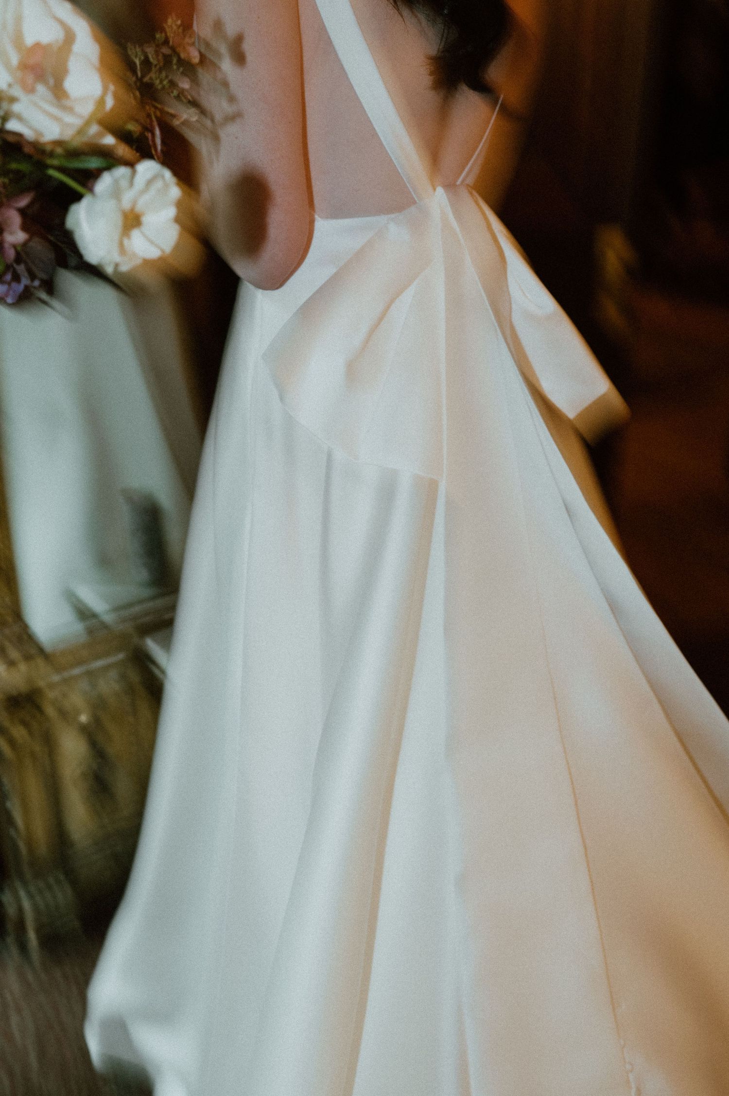 Detail shot of an elegant white wedding dress with bow detail.