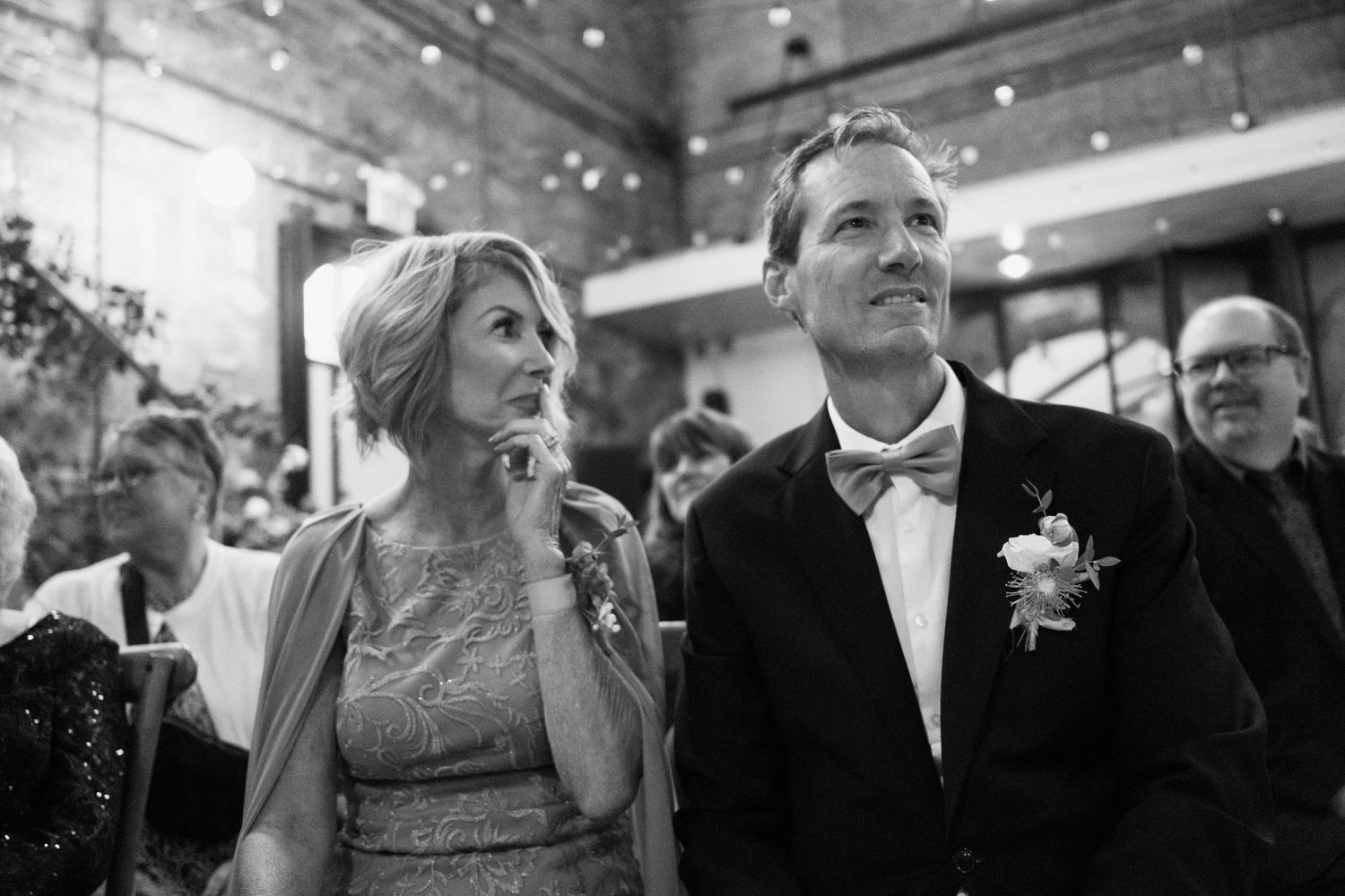 A black and white candid shot of wedding guests watching the celebration.