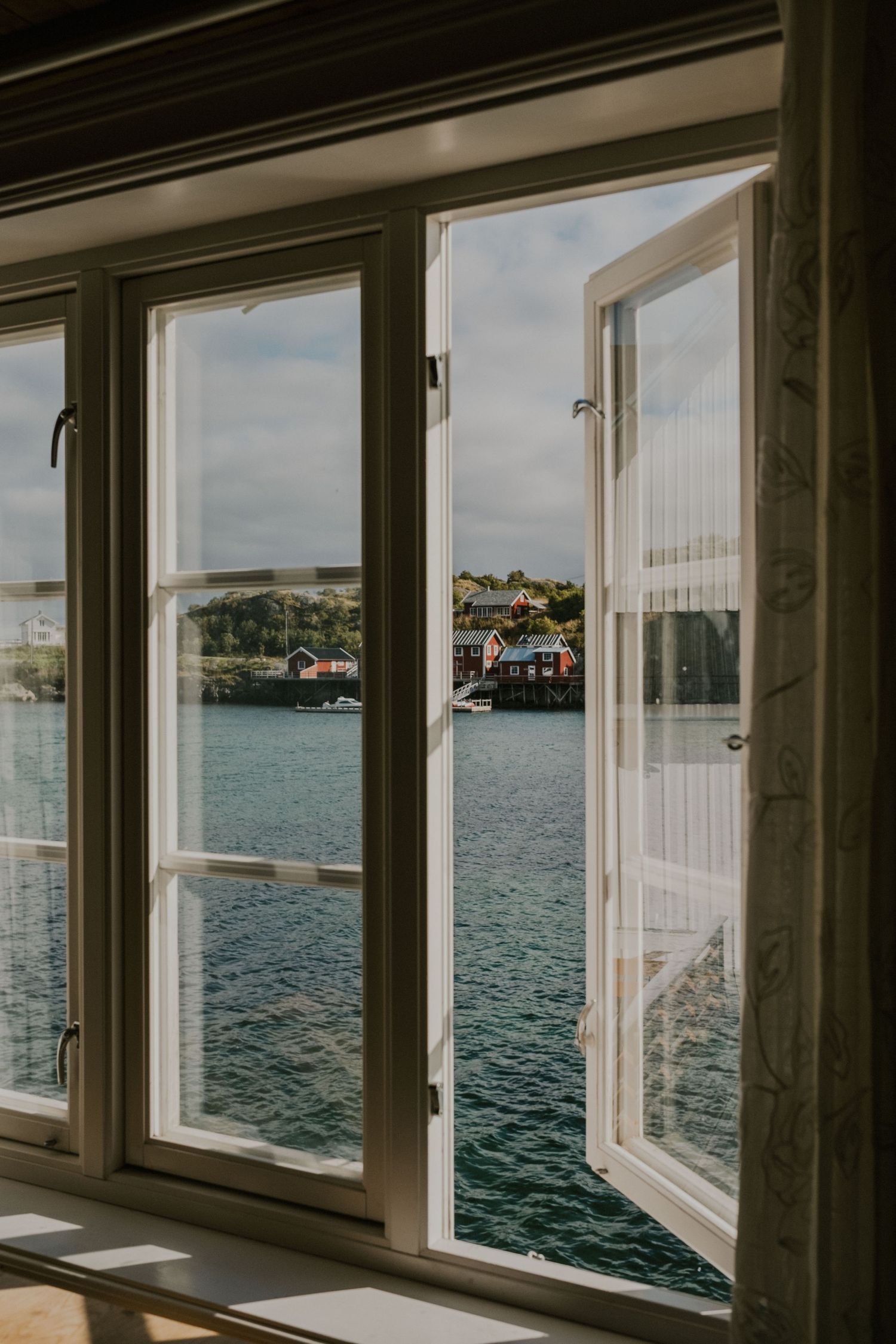 View of coastal village through open windows overlooking tranquil harbor waters.