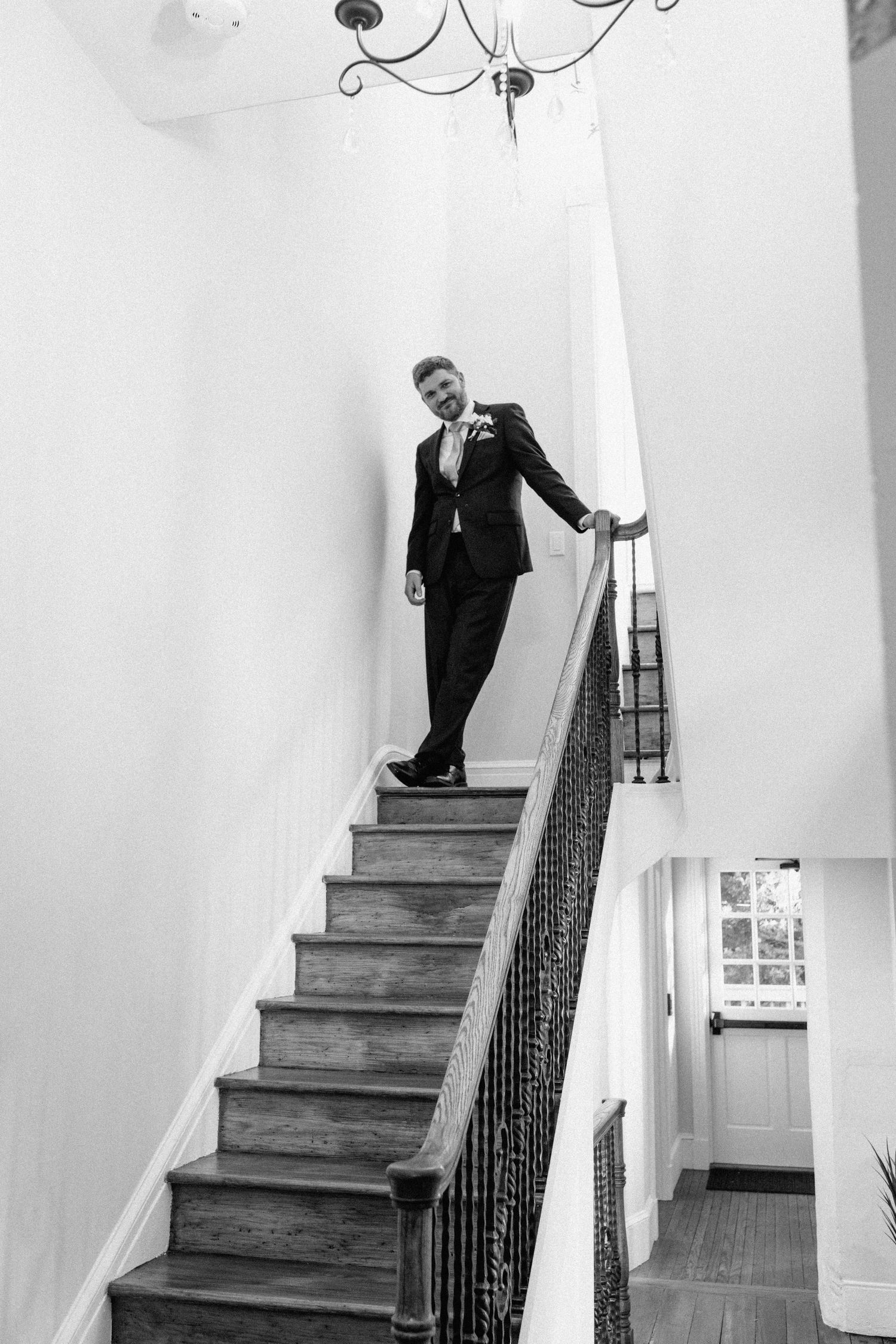 Classic black and white portrait of someone descending an elegant staircase with wrought iron railing.