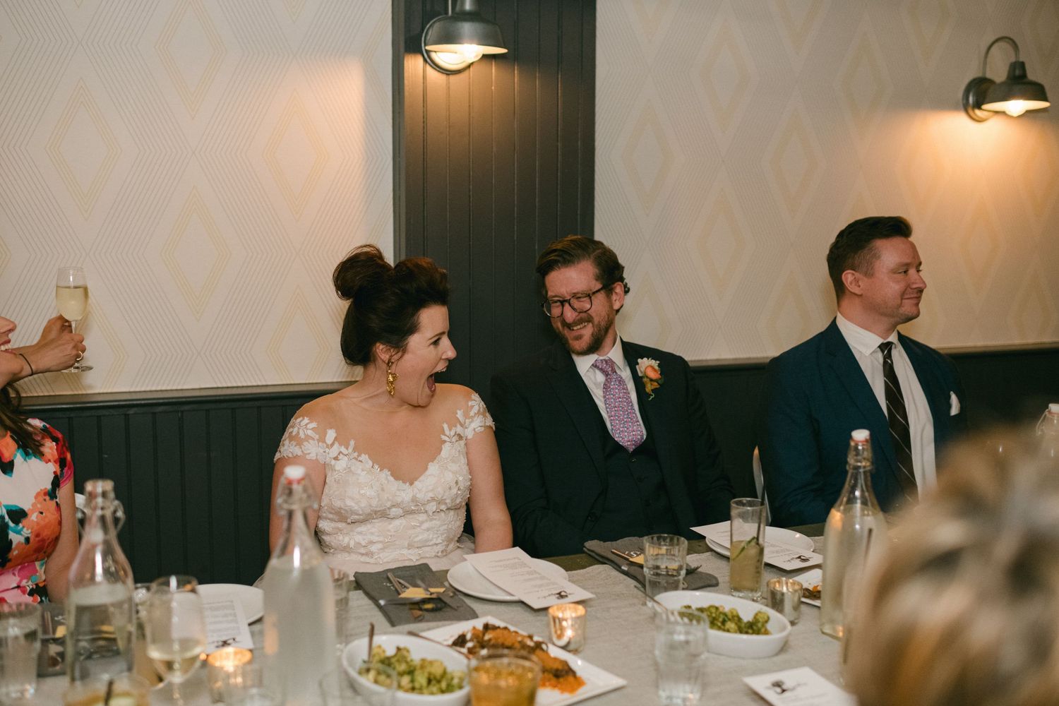 Wedding guests enjoying dinner at an intimate restaurant reception.