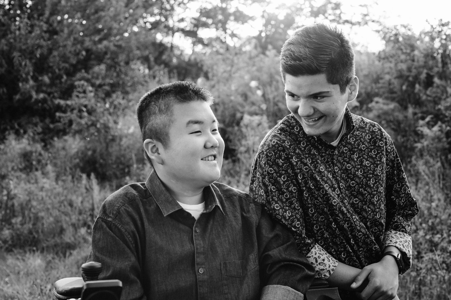 Black and white candid portrait of two people sharing a joyful moment outdoors.
