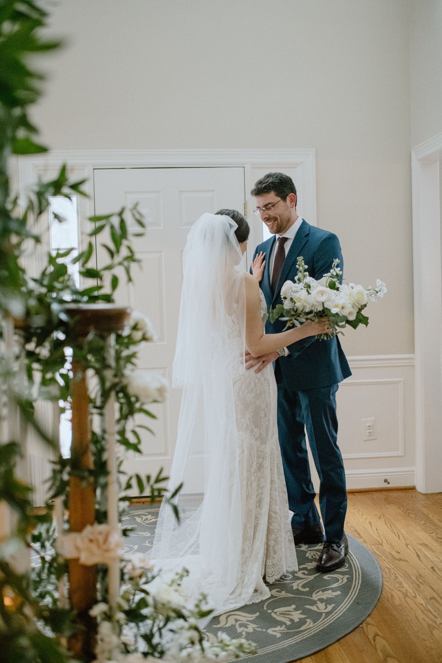 A couple shares a tender moment surrounded by decorative greenery during their wedding ceremony.
