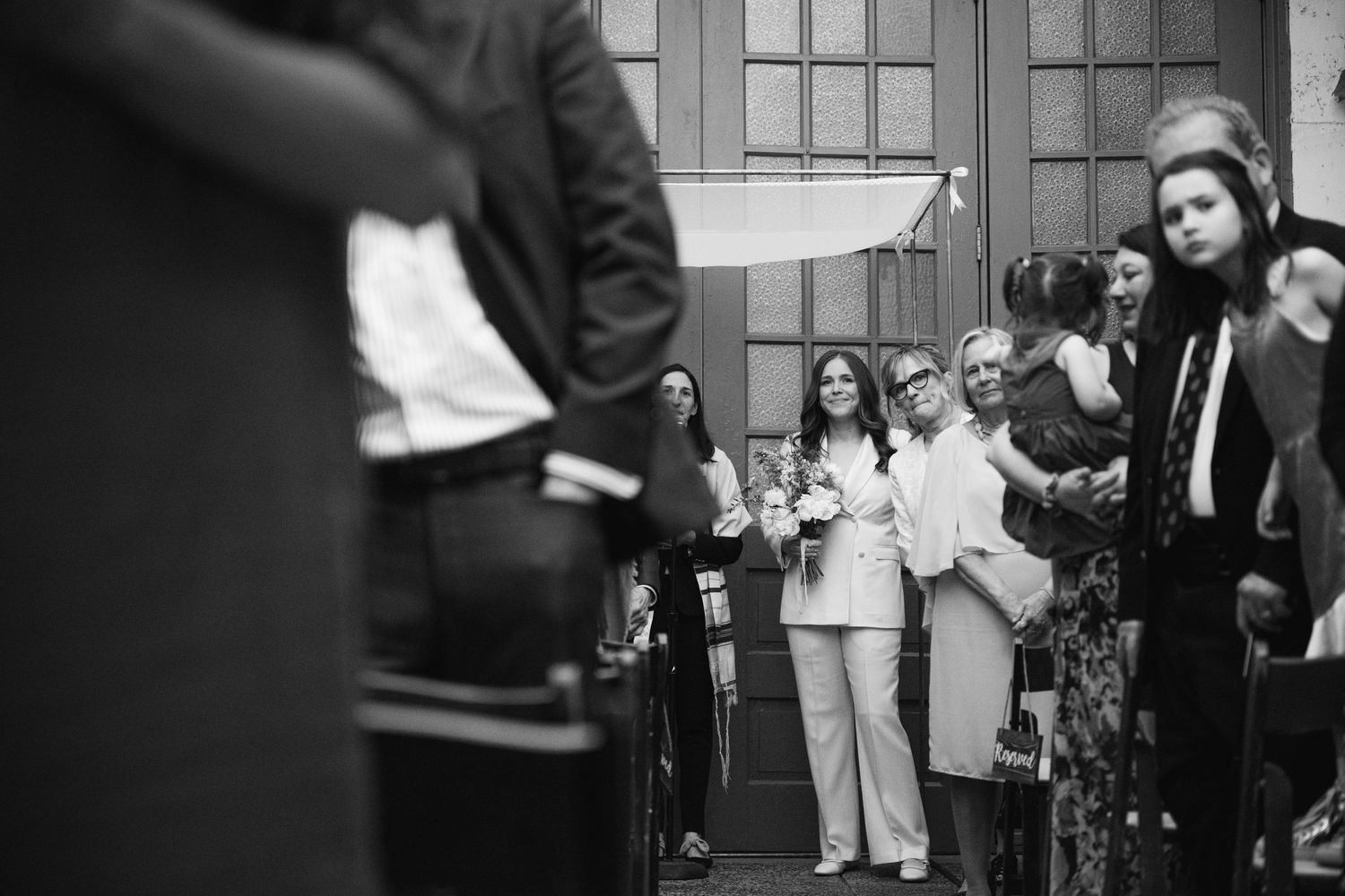 Wedding guests gathered outside venue during daytime celebration.