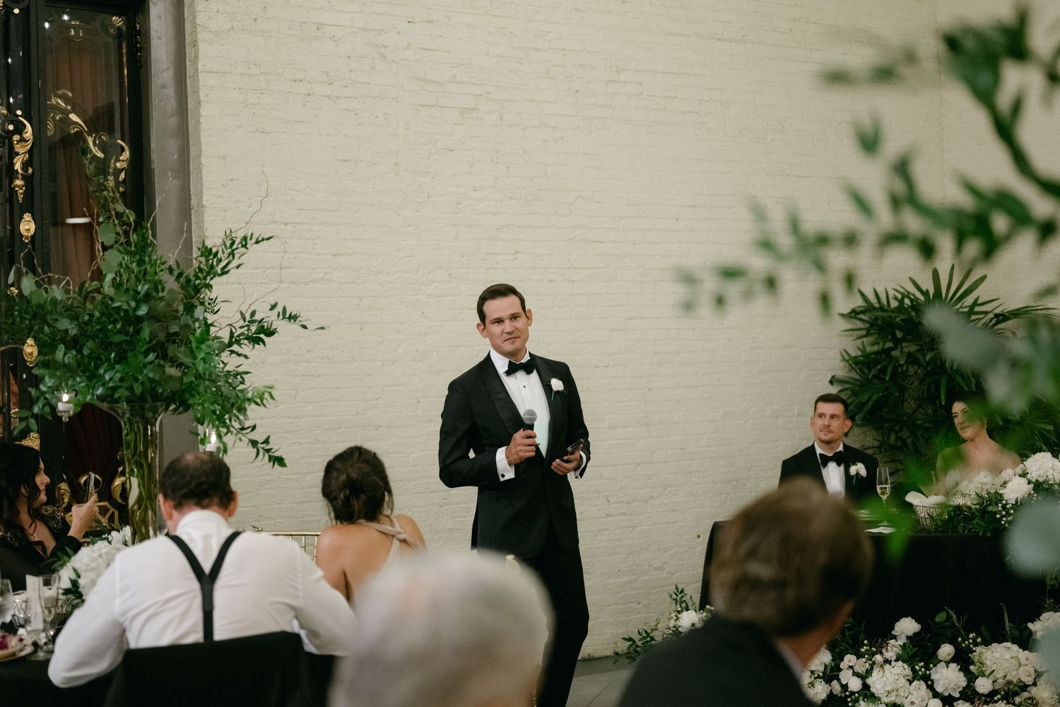 Wedding reception speech being given in an intimate garden setting with string lights.