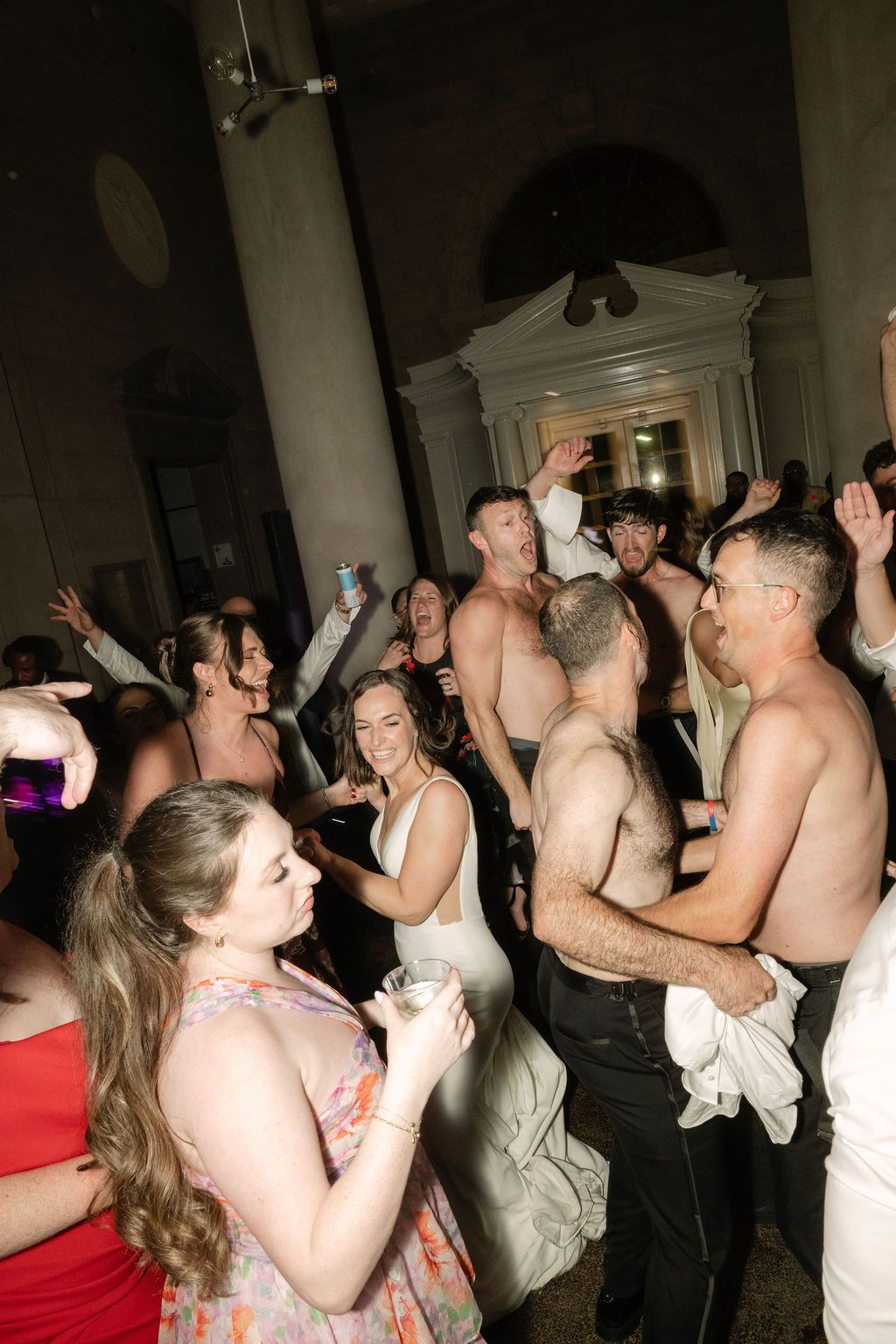 People dancing energetically at a crowded party with their arms raised in celebration.