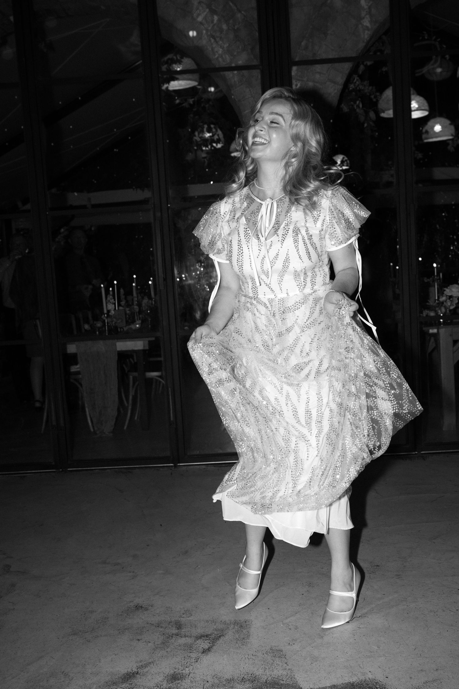 Person twirling in a white vintage-style dress during a party in black and white photography.