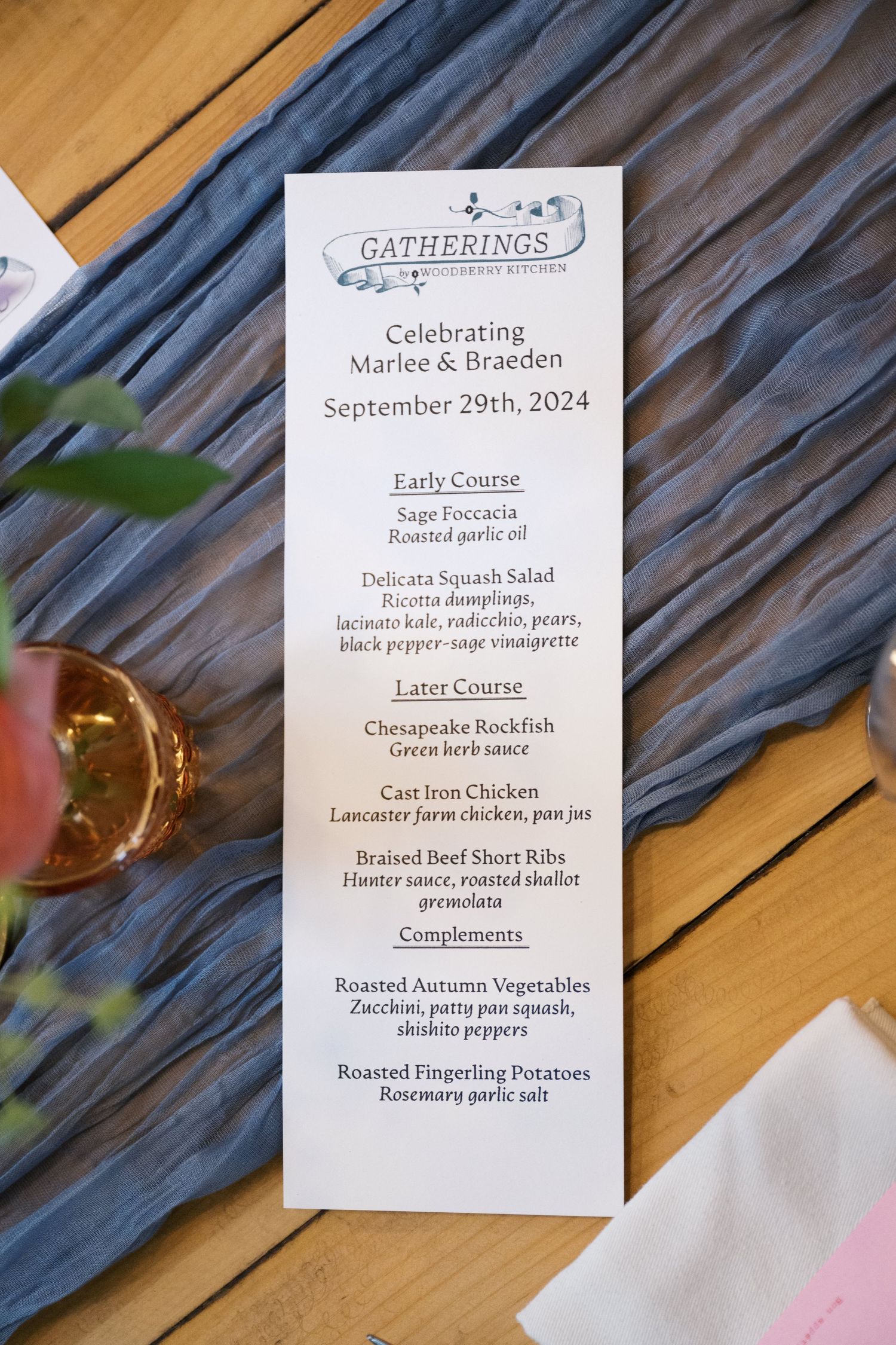 Wedding menu card for Gatherings event with early and later course details on blue fabric runner.