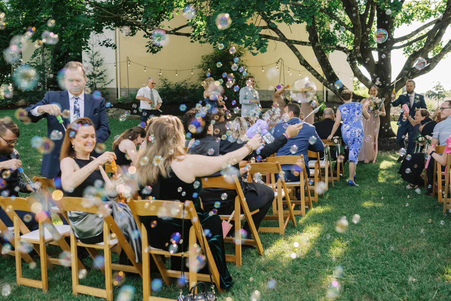 Guests seated in wooden chairs during an outdoor garden wedding ceremony.