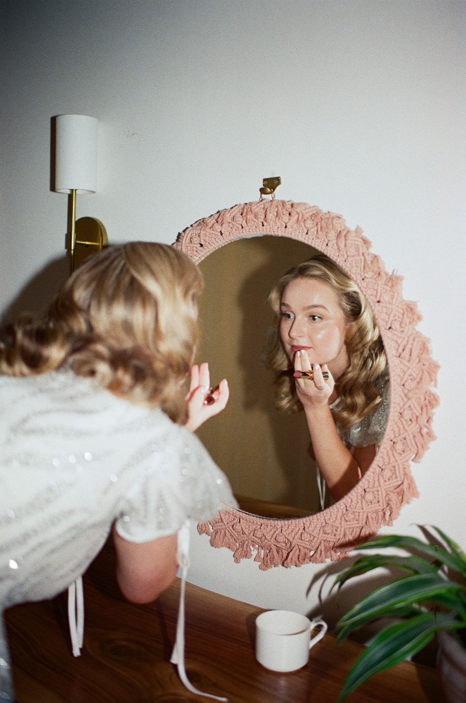 Reflection in pink decorative mirror shows wedding day preparations and styling.